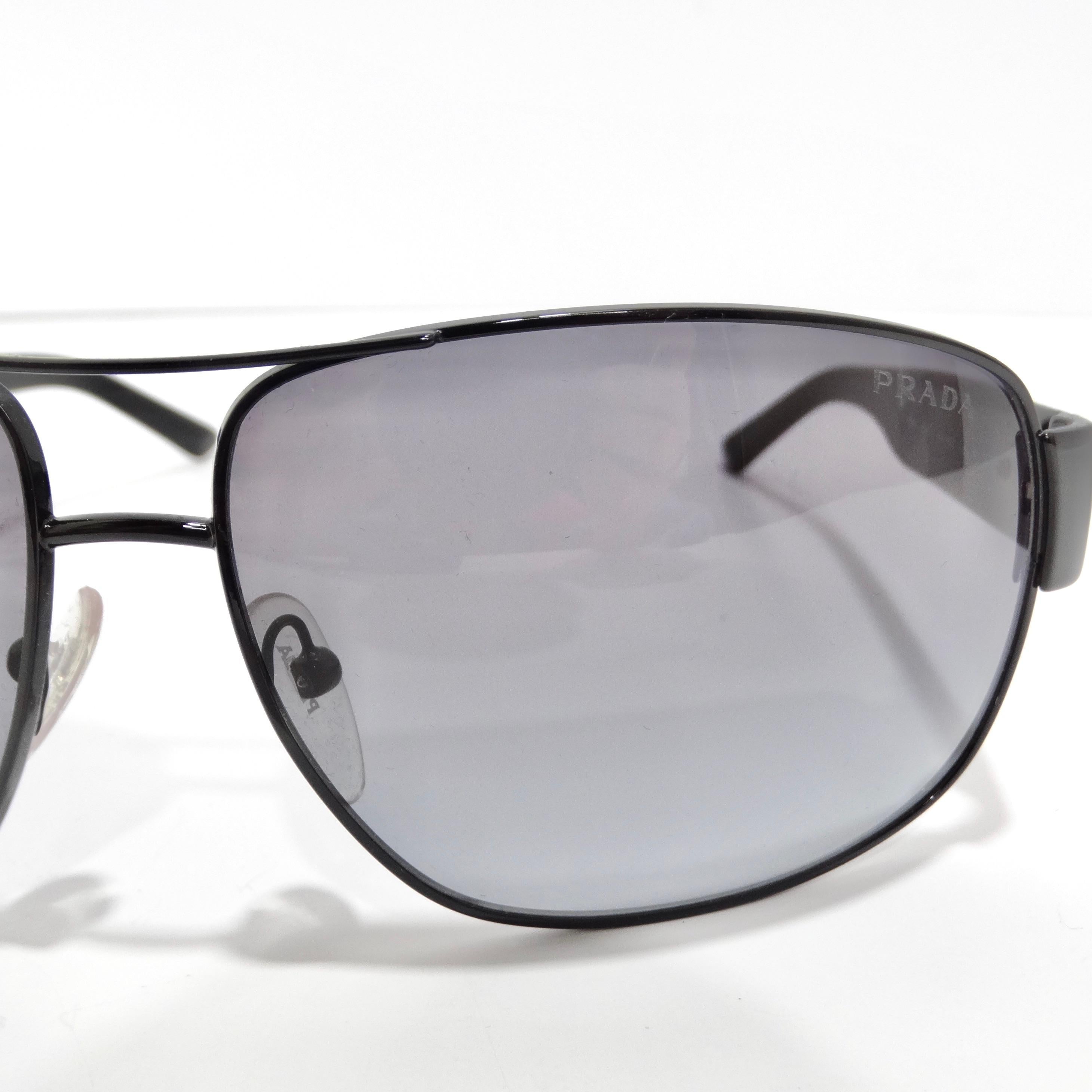 Indulge in vintage-inspired elegance with the Prada 1990s Black Linea Rossa Sunglasses, a classic aviator style that exudes timeless chic and style. These sunglasses showcase thin black rims paired with black arms featuring silver-tone Prada logos,