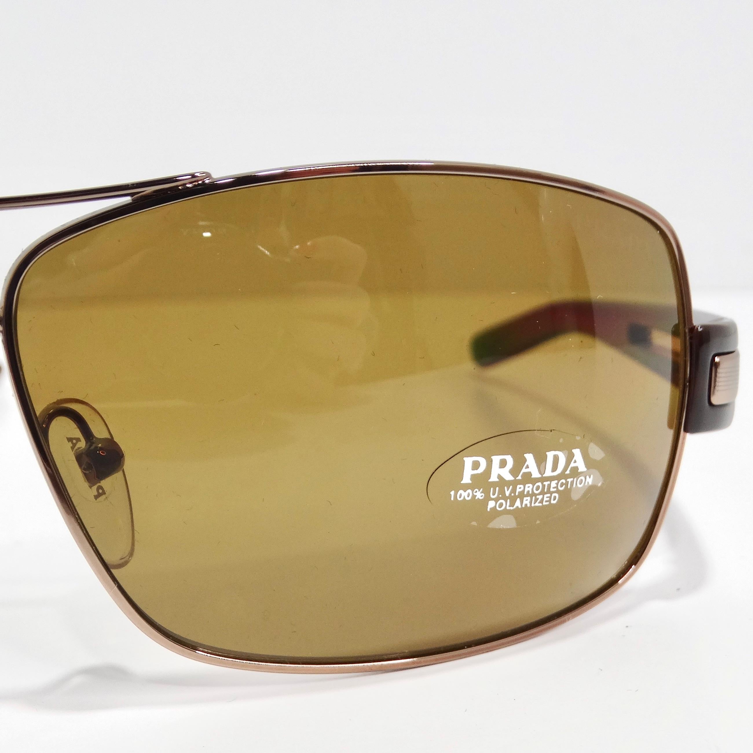 Les lunettes de soleil Aviator Prada 1990 marron sont des lunettes de soleil de style aviateur classique, d'un chic et d'une sophistication intemporels. Ces lunettes de soleil présentent de fins bords dorés, associés à des branches brunes ornées de