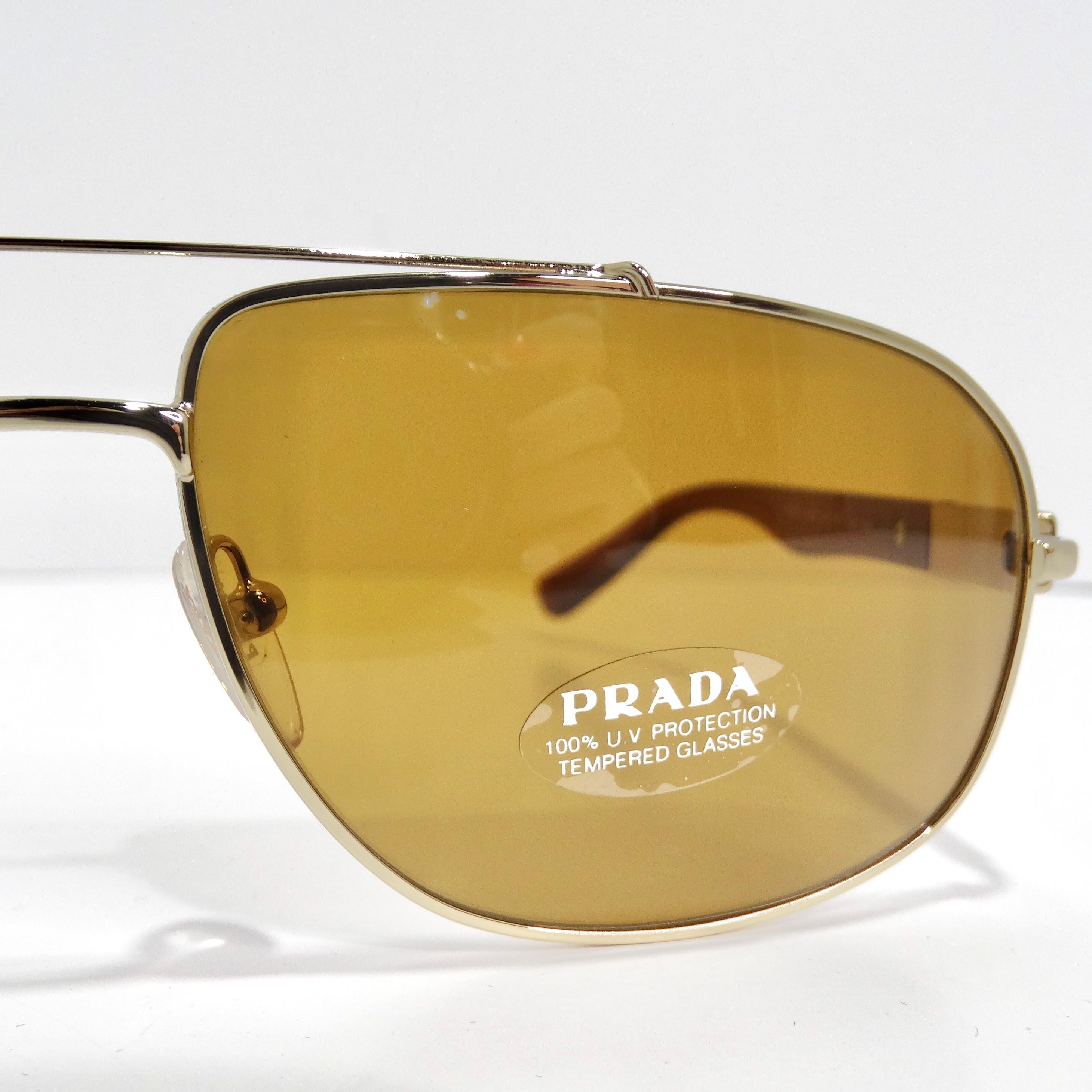 Elevate your eyewear collection with the Prada 1990s Brown Gold Tone Aviator Sunglasses, a classic aviator style that exudes timeless chic and sophistication. These sunglasses showcase thin gold-tone rims paired with brown arms adorned with