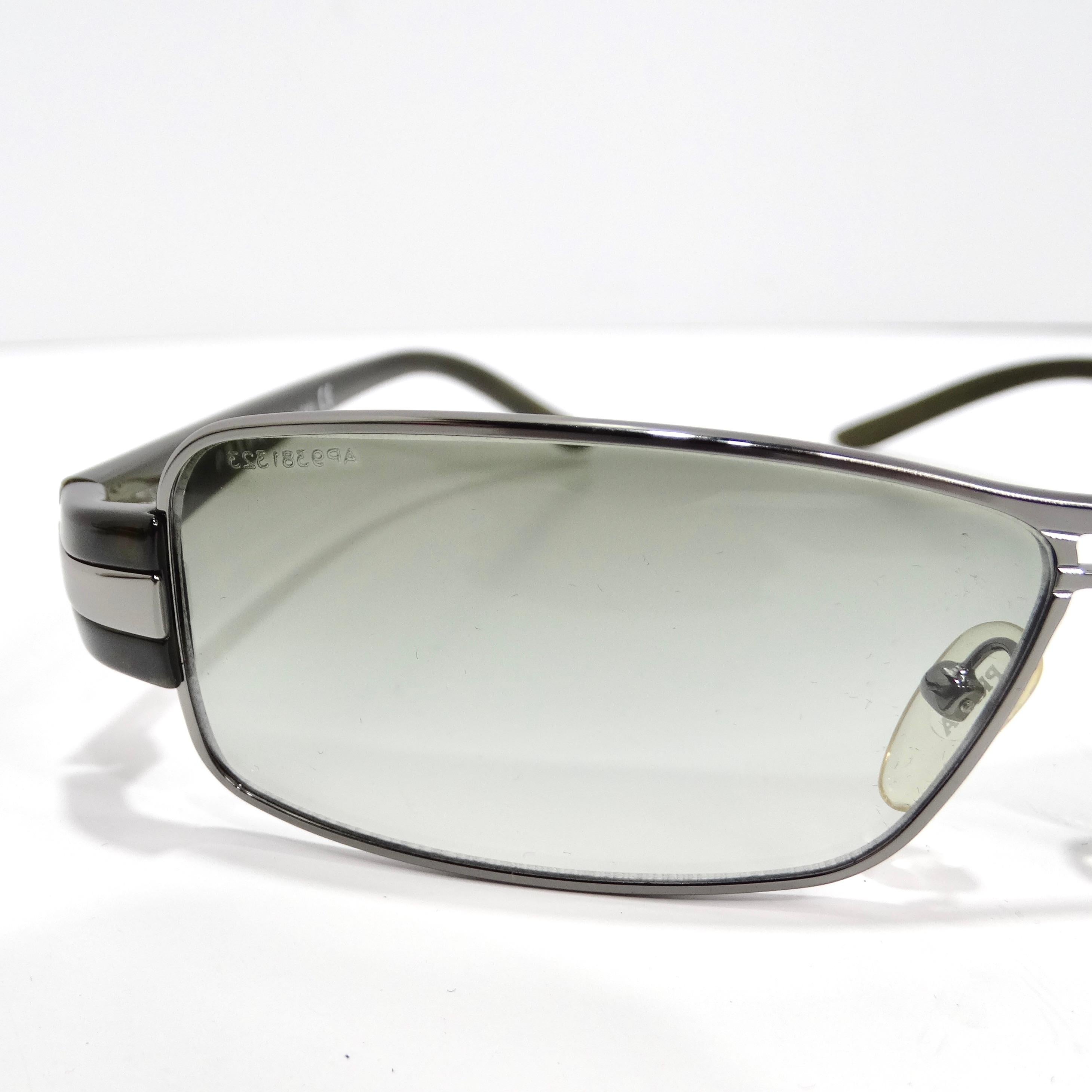 Step into a timeless era of fashion with the Prada 1990s Silver Tone Green Rectangular Sunglasses, a classic accessory that combines sophistication with a touch of vintage charm. These sunglasses feature thin silver-tone rims, paired with green arms