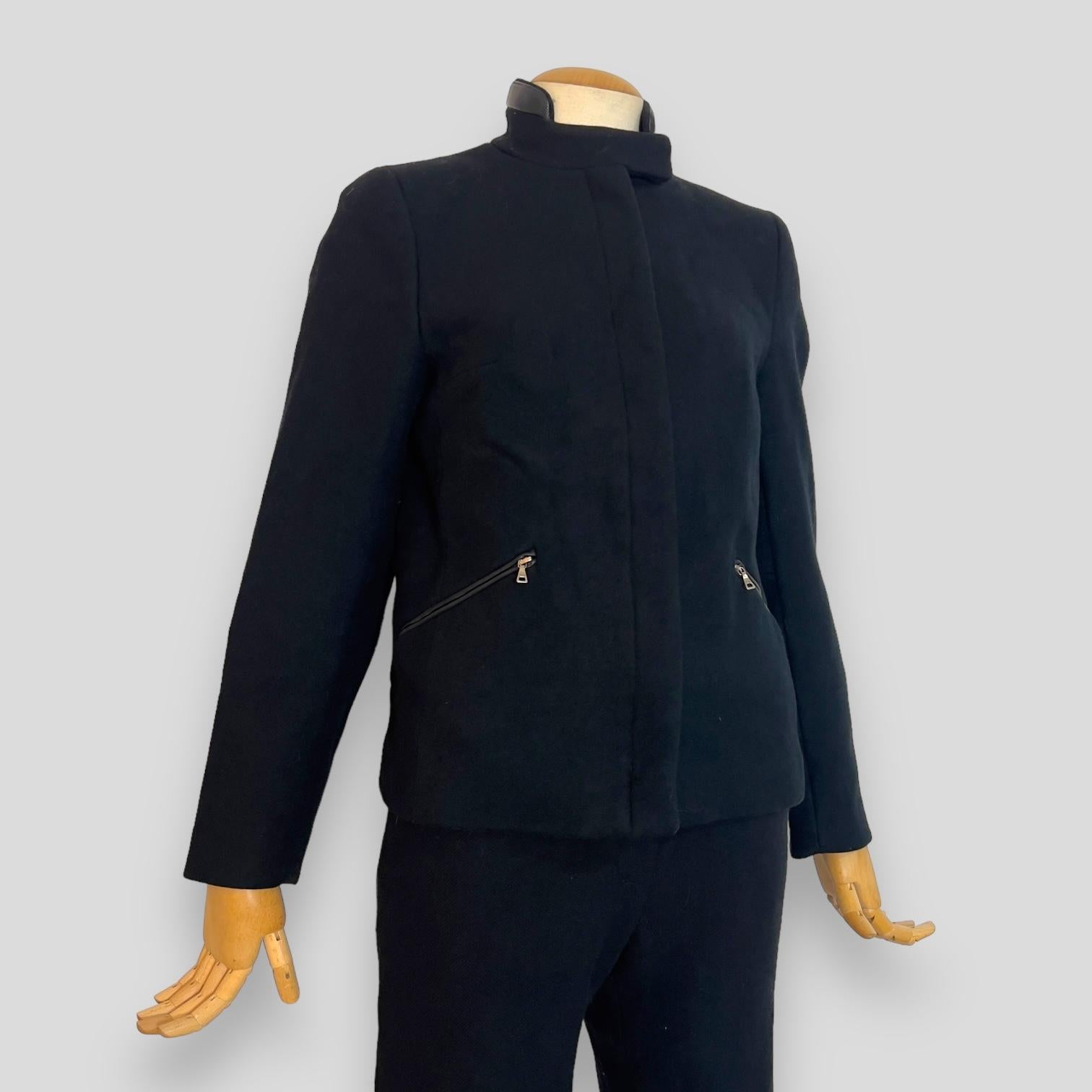 This Prada Fall/Winter 1999 black wool jacket with matching capri pants epitomizes sophistication and timeless style. Crafted from 100% wool, the jacket features luxurious leather elbow patches and leather detailing, including a leather Prada label.