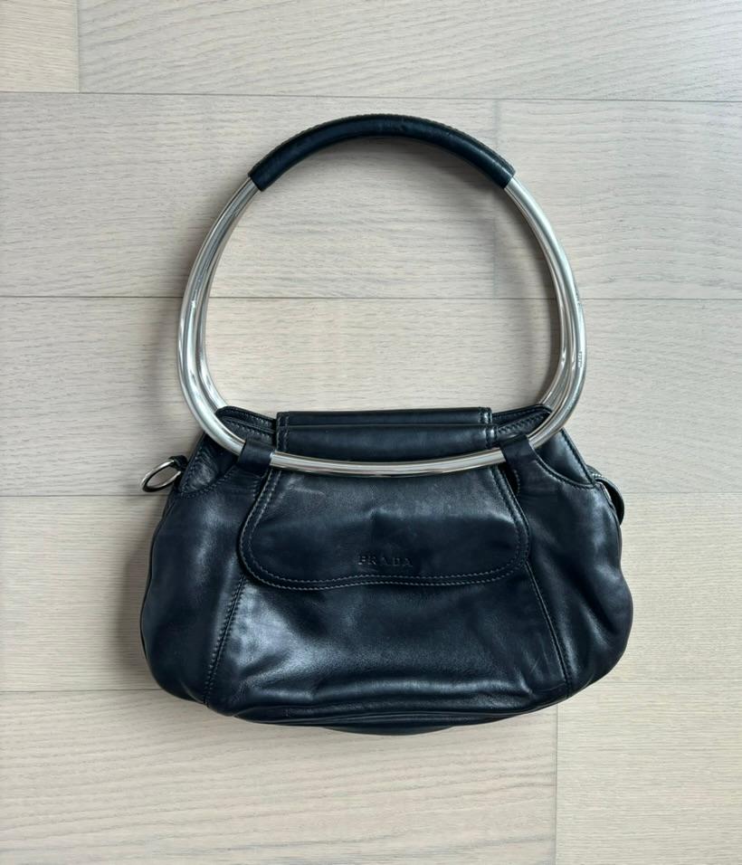 Prada
SS03
Vintage
Runway
Jet black SOFT AF lambskin leather with silver hardware
Excellent vintage condition
Measurements in inches laying flat: length of entire bag 16, length of armhole 8 x 9.5, width of bag 13 at largest, depth of bag 3

FINAL