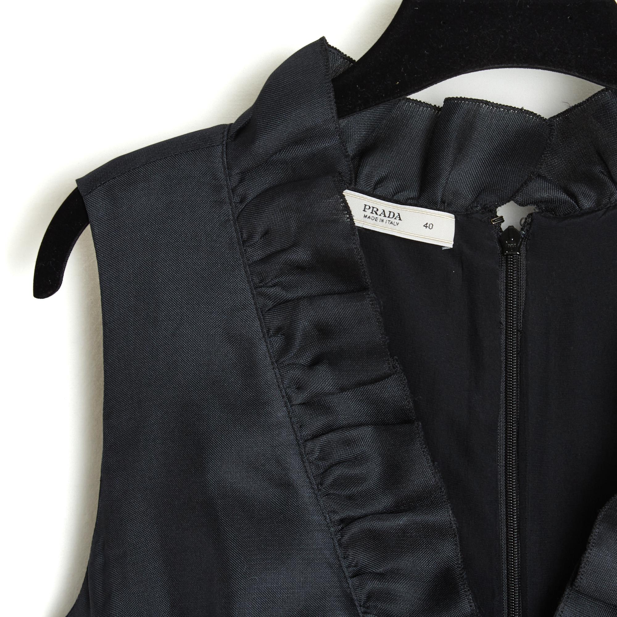 Prada Kleid circa 2006 aus schwarzem Seidenorganza, V-Ausschnitt mit Rüsche am Hals und in der gesamten Länge sowie am unteren Rand des Rocks, Wickel, Gürtel und Schleife aus schwarzem Satinband unter der Brust angenäht, Verschluss durch einen