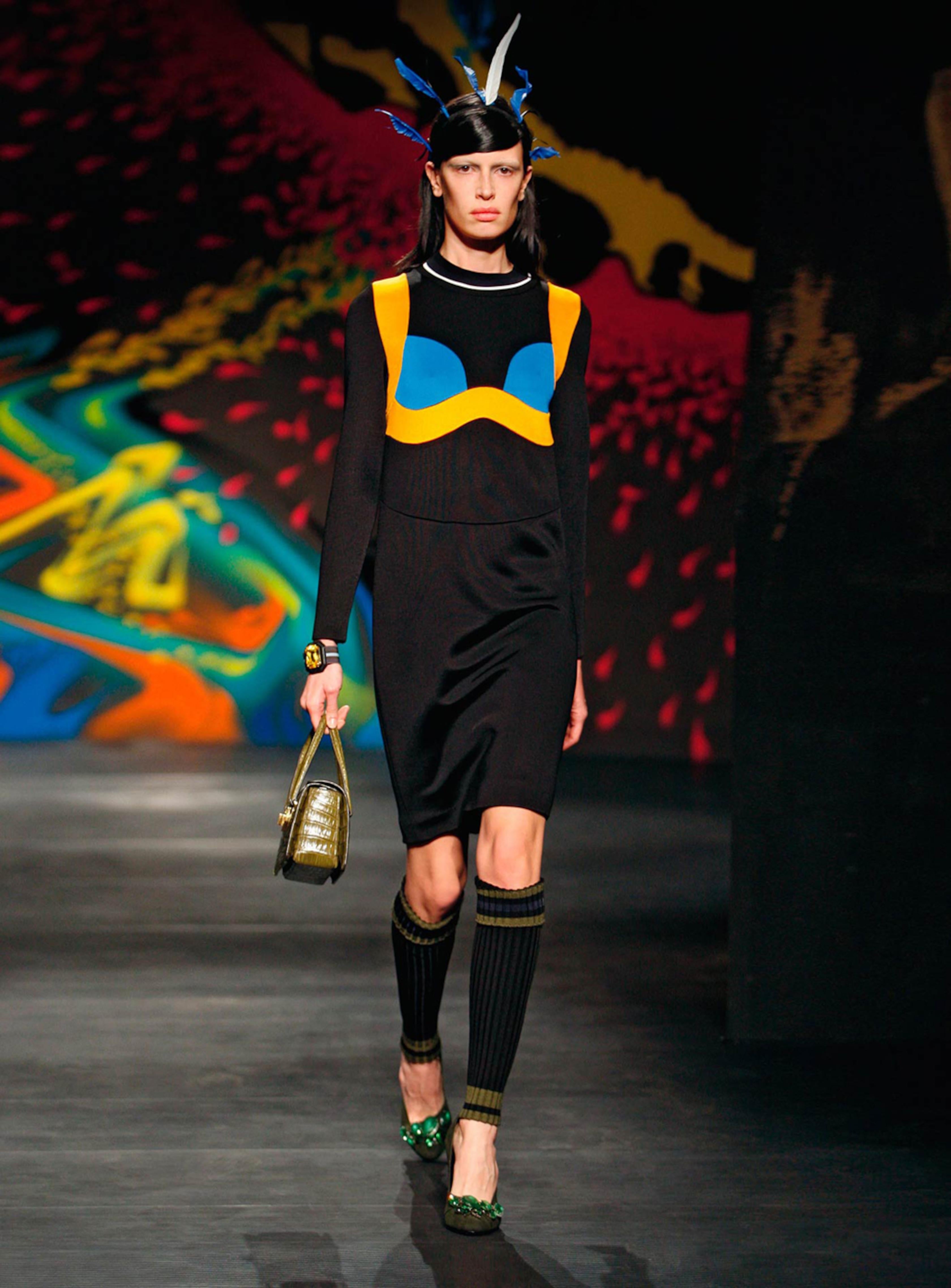 From the Prada 2014 SS runway and ad campaign, this knee length black dress features a trompe l'oeil bra in contrasting blue and gold, and a white and dark navy band on the ribbed collar. Can be dressed up or down easily with the right accessory.