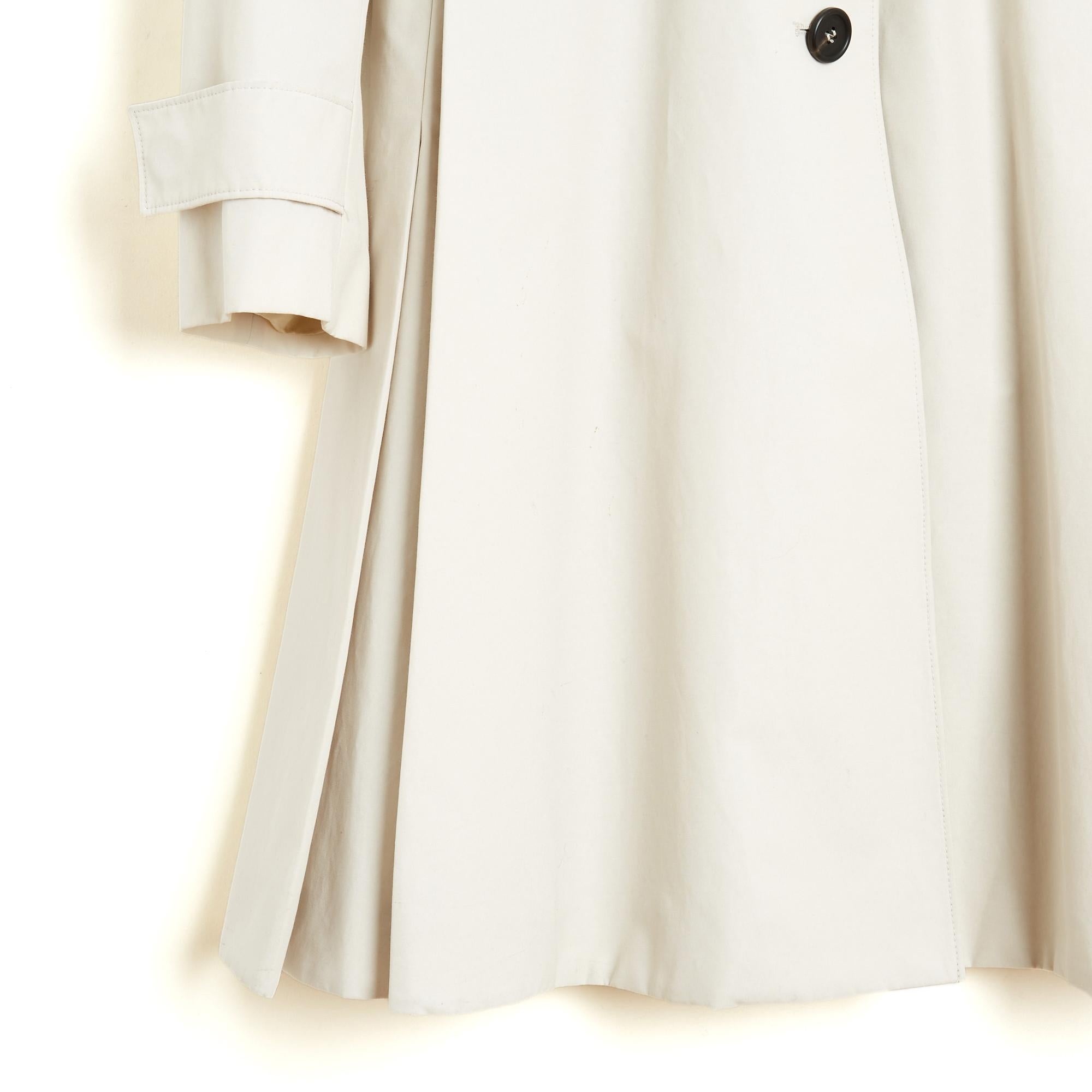 Prada 2016 trench coat in ecru cotton and polyester gabardine, straight cut, classic collar closed by 5 buttons and a wide belt, on belt loops, with silver metal pin buckle, 2 large box pleats in front hiding the slit pockets, 3 large box pleats in