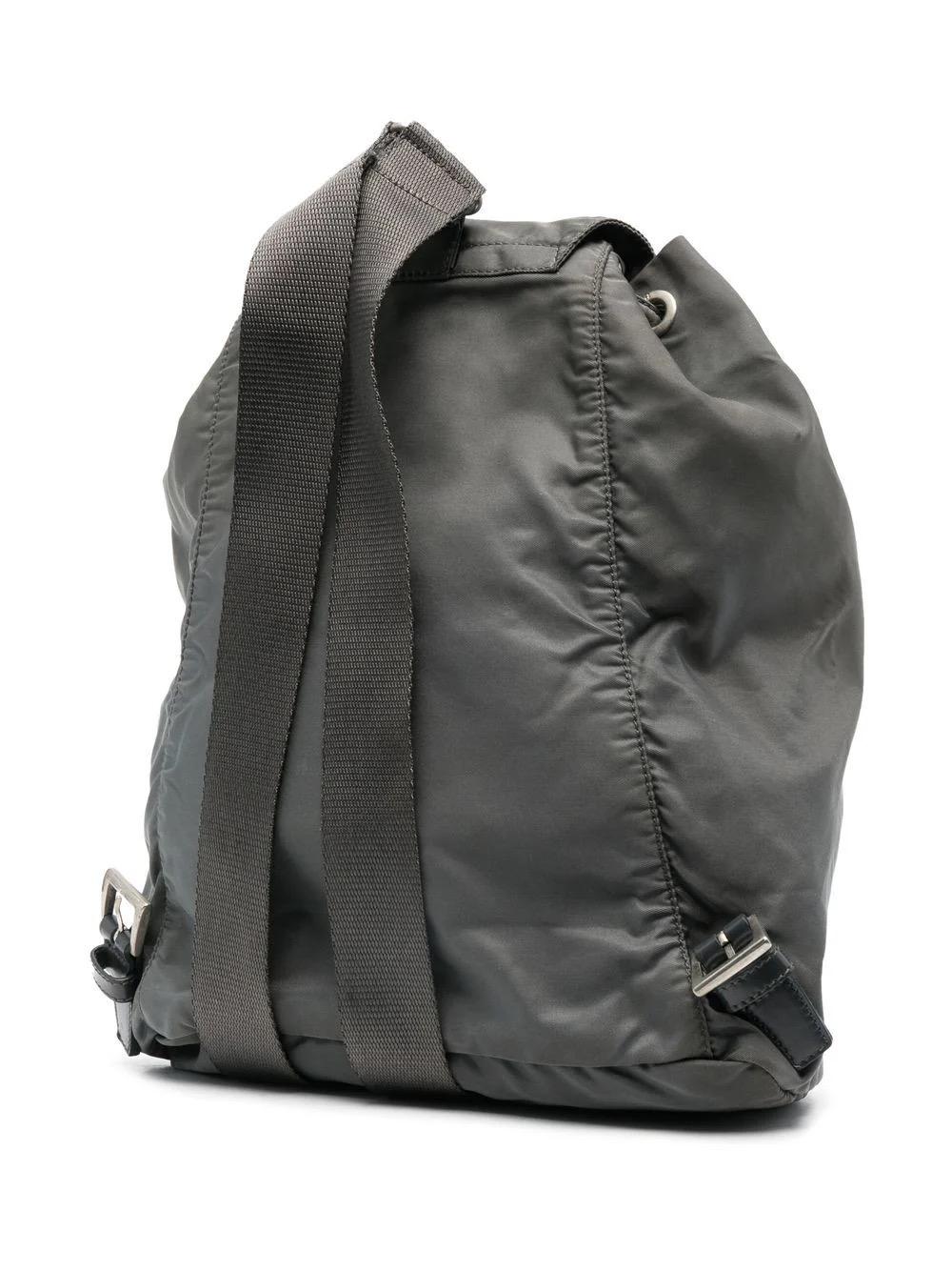 Prada Grey nylon Tessuto triangle logo drawstring backpack bag featuring enamel triangle logo, single top handle, two adjustable shoulder straps, foldover top, buckle-strap fastening, drawstring fastening, front zip-fastening compartment, internal