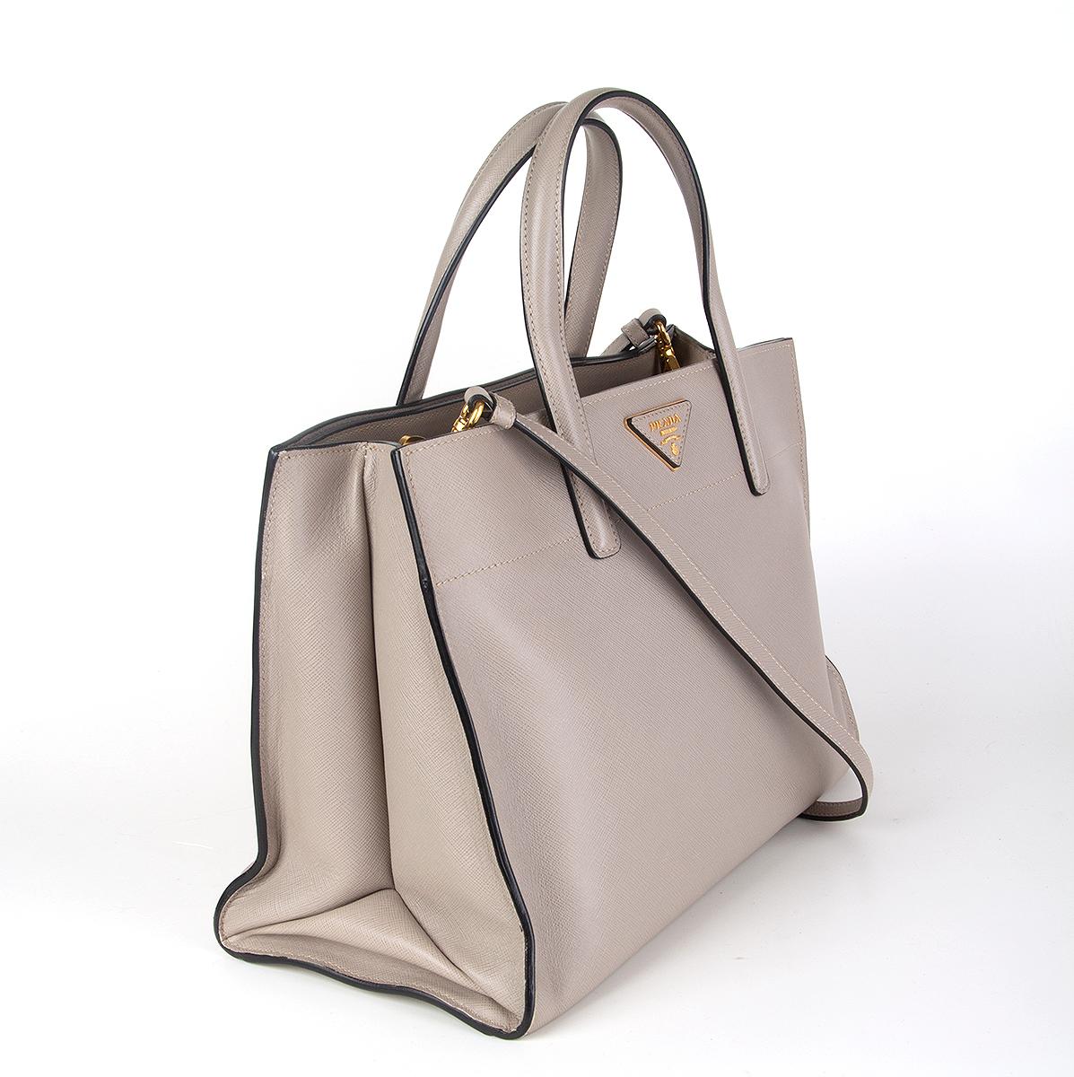 
100% authentic Prada top-handle shoulder bag in taupe Saffiano leather featuring gold-tone hardware. Interior is divided in three compartments with a zipper pocket against the back and the front with two open pockets on top. Zipper pocket in the