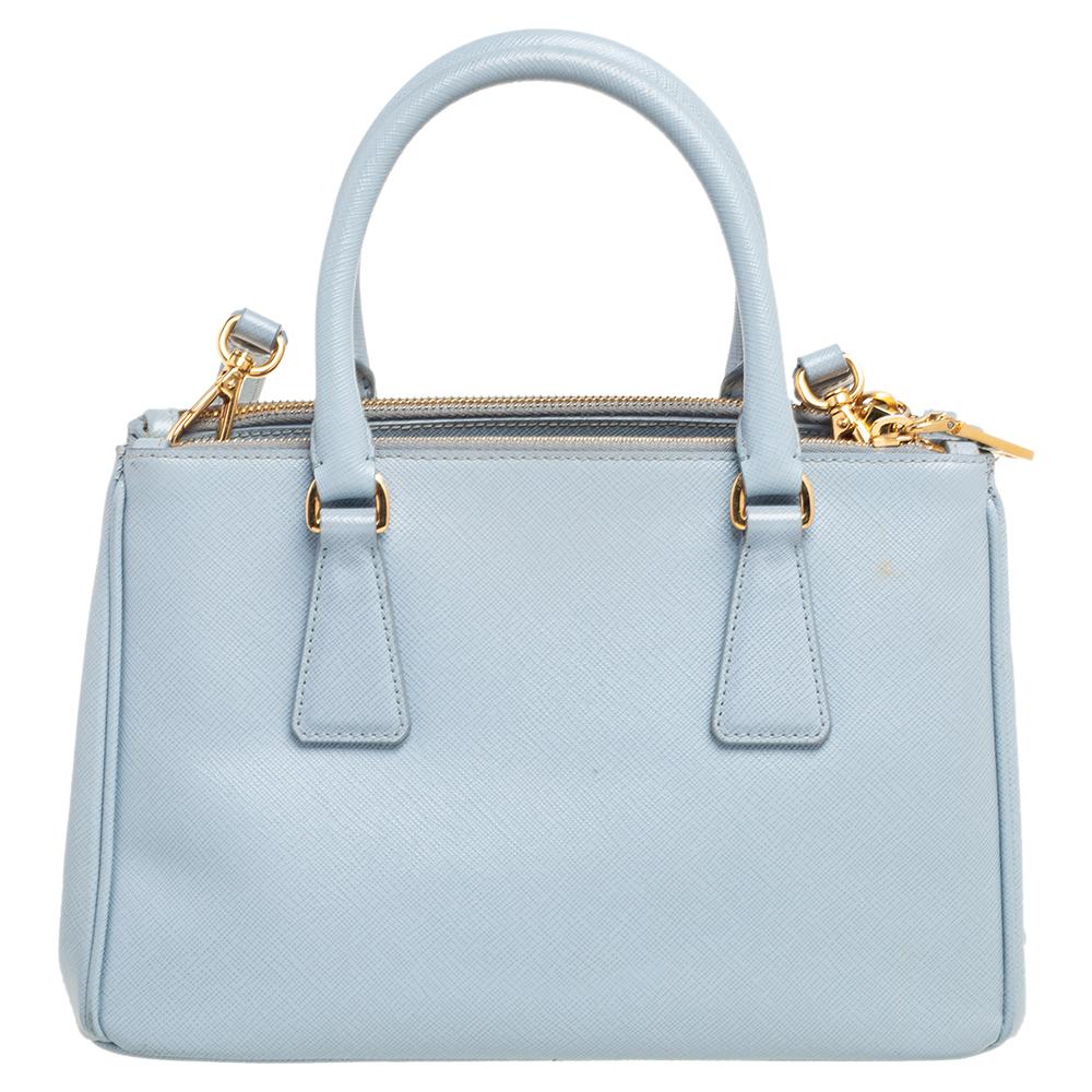 Loved for its classic appeal and functional design, Galleria is one of the most iconic and popular bags from the house of Prada. This beauty in baby blue is crafted from Saffiano Lux leather and is equipped with two top handles, the brand logo on