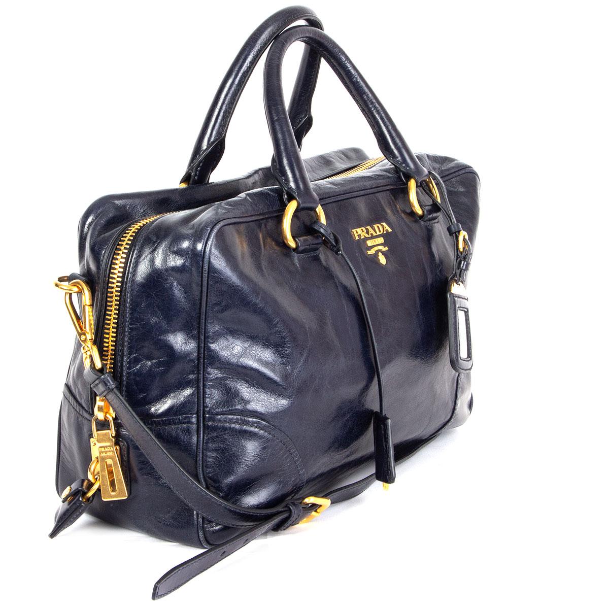 100% authentic Prada Medium Bauletto Bag Vitelli in midnight blue shiney leather featuring gold-tone hardware. Opens with a zipper on top and is lined in midnight blue signature nylon with one zipper pocket against the back with an open pocket