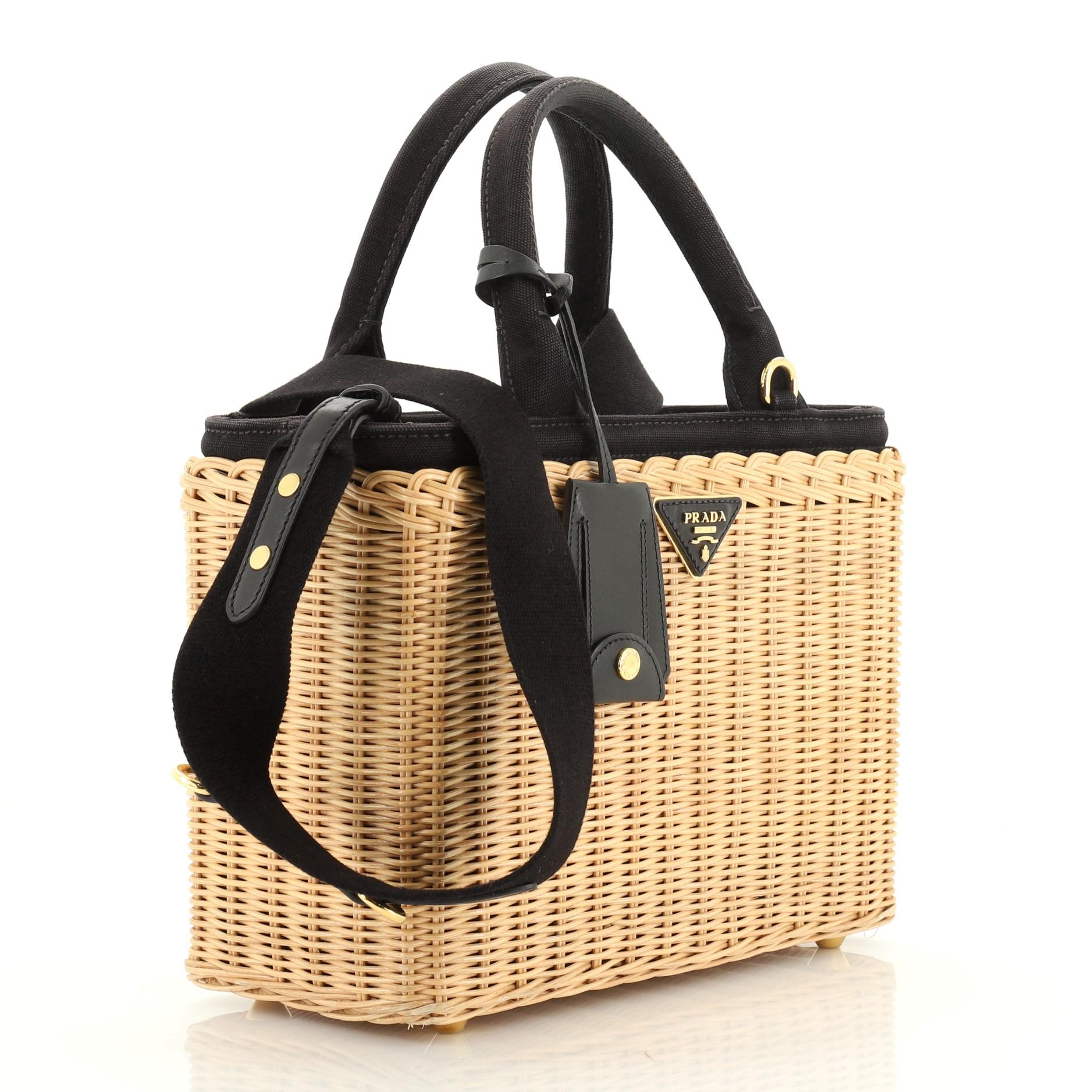 This Prada Basket Bag Wicker with Canapa Small, crafted from neutral wicker with canapa, features dual rolled handles, triangle Prada logo, tassel accent, and gold-tone hardware. Its zip closure opens to a black fabric interior. 

Estimated Retail