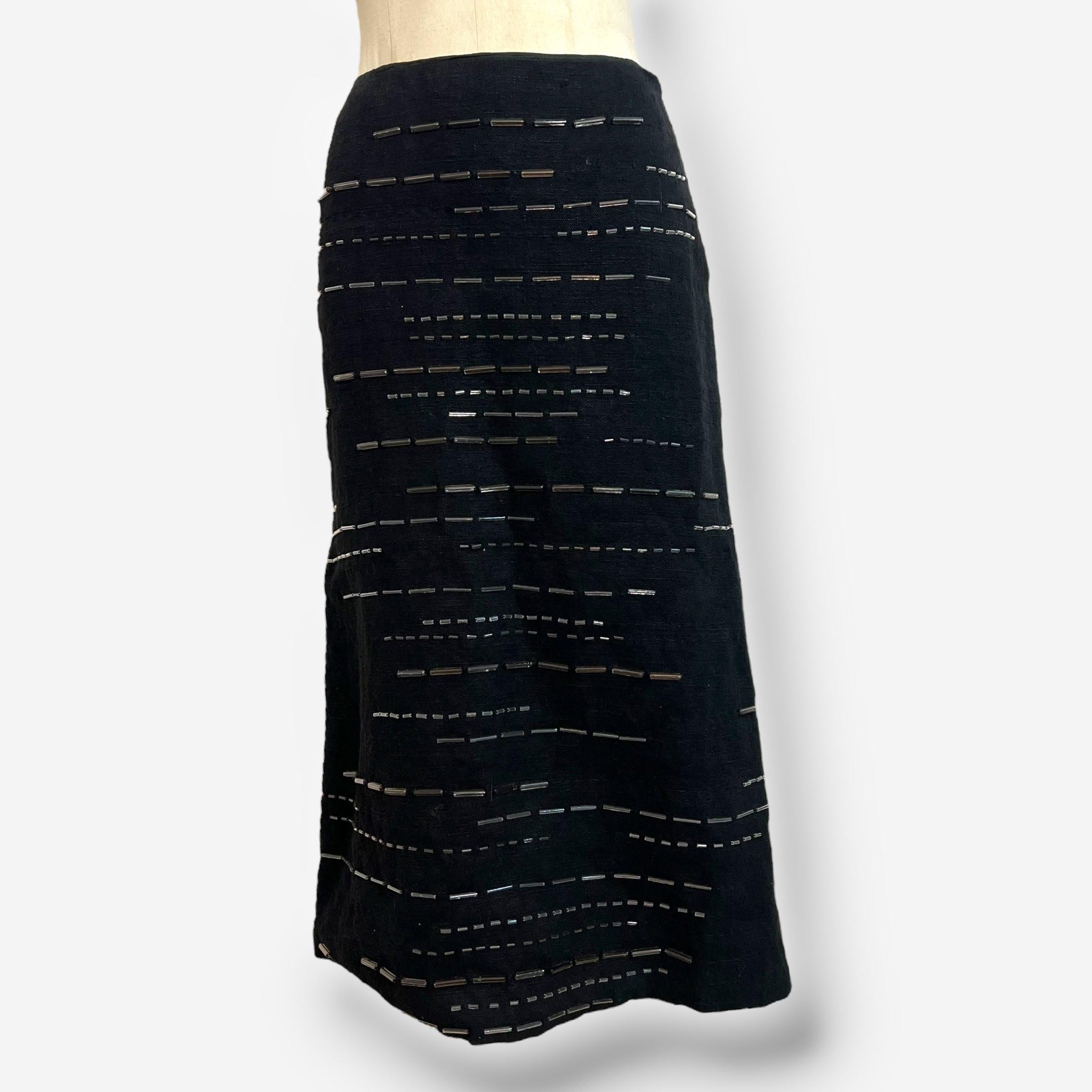 
Elegant and understated, this black Prada skirt from the Spring/Summer 1998 collection features a midi silhouette crafted from high-quality linen. The surface is meticulously adorned with horizontal rows of tonal glass seed beads, offering delicate