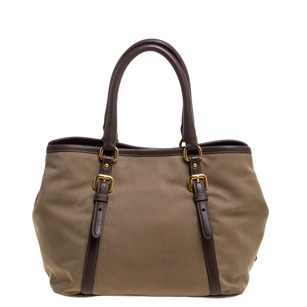 This bag from Prada offers a comfortable style. This shoulder bag is crafted in canvas with leather trim detailing. It also features gold-tone hardware, the brand logo embroidery, and a leather bow on the front. The snap button fastening on the top