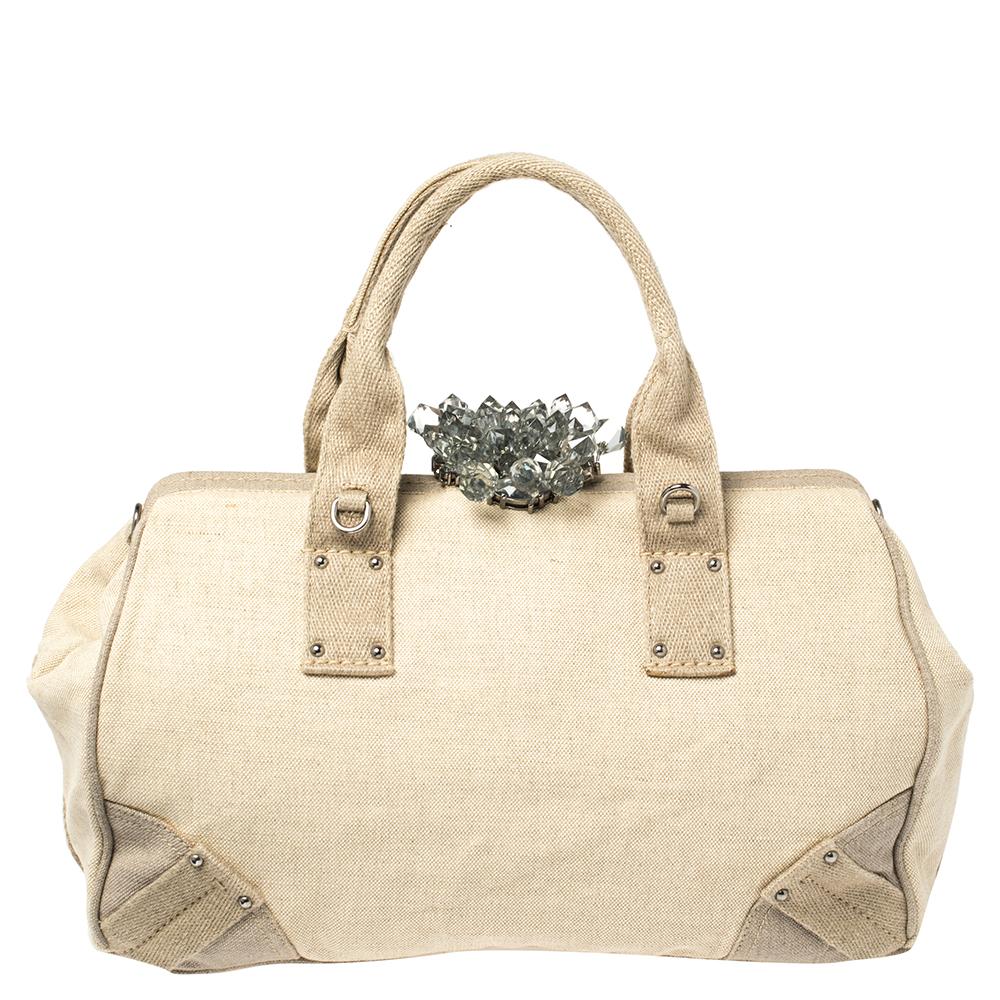 Add a touch of minimized elegance when you style this Prada bag with your favorite accessories. This beige-hued bag is made of canvas and has a framed top accented with a notable crystal lock. The logo-accented front flap opens to a spacious