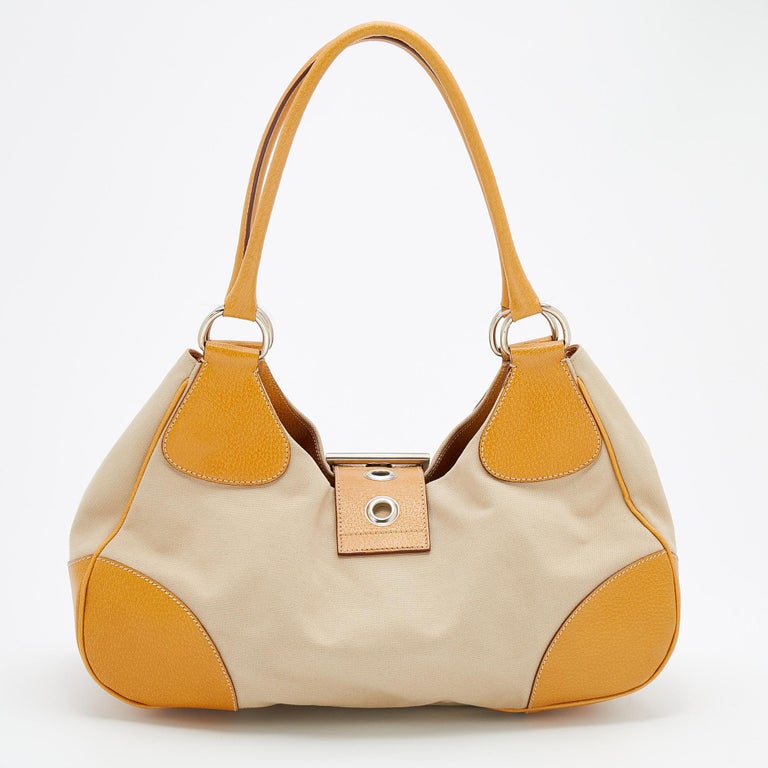 Designed perfectly for your day-to-night endeavors, this chic bag from Prada is worth every penny. Comfortable and easy to carry, this canvas and leather creation comes with a buckle closure on the front. It features dual handles at the top and a