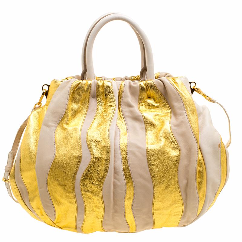 Who says your everyday wear bags have to be neutral and basic? This stunning Prada hobo is the one to make a statement and a perfect saviour when you need to impromptu attend a party or an event. Crafted in beige and gold stripes leather, this