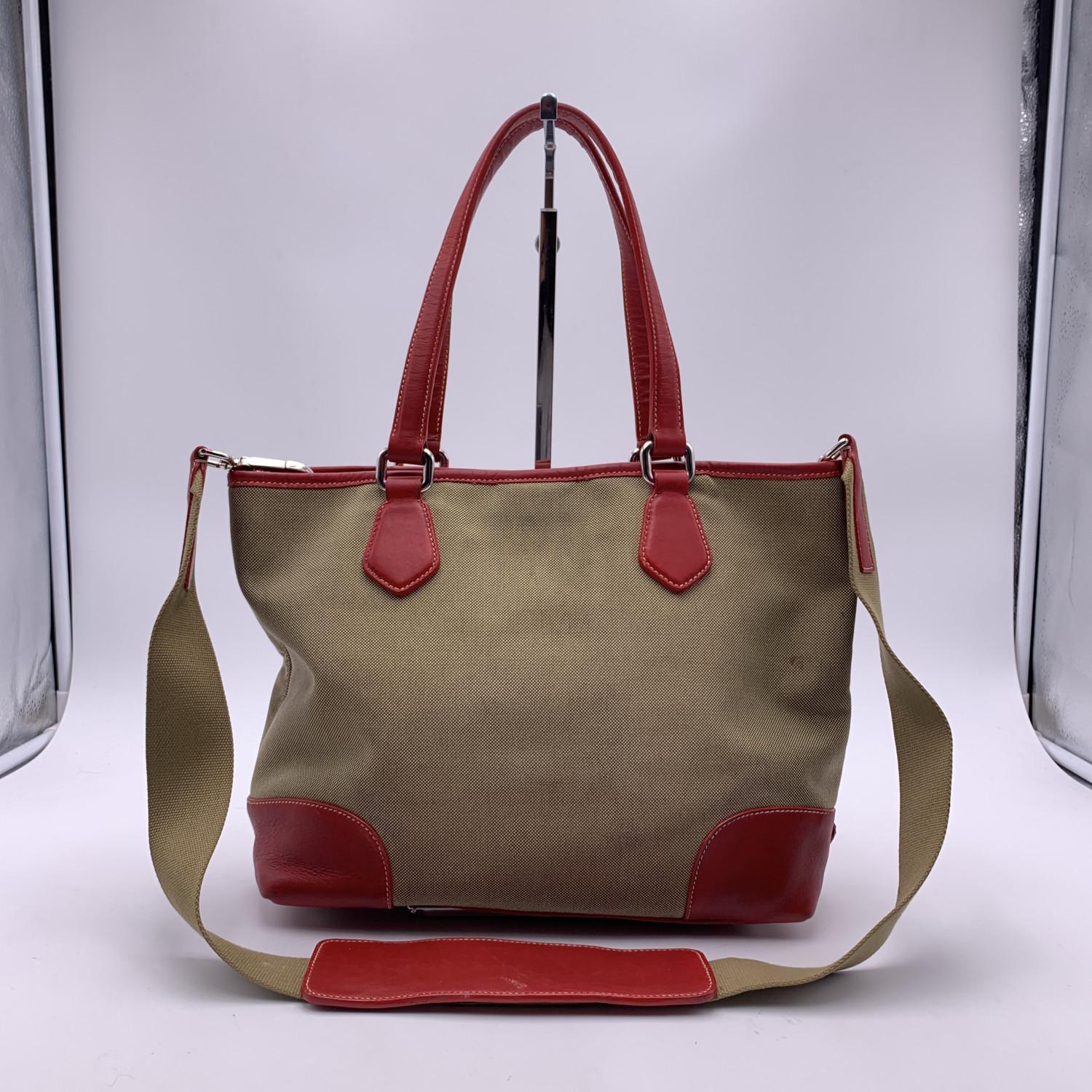 PRADA jacquard logo tote bag. Contemporary design and an edgy bold look. Beige canvas and red leather trim. Magnetic button closure on top. Silver metal hardware. PRADA signature lining . 1 side zip pocket inside. Removable canvas shoulder strap.