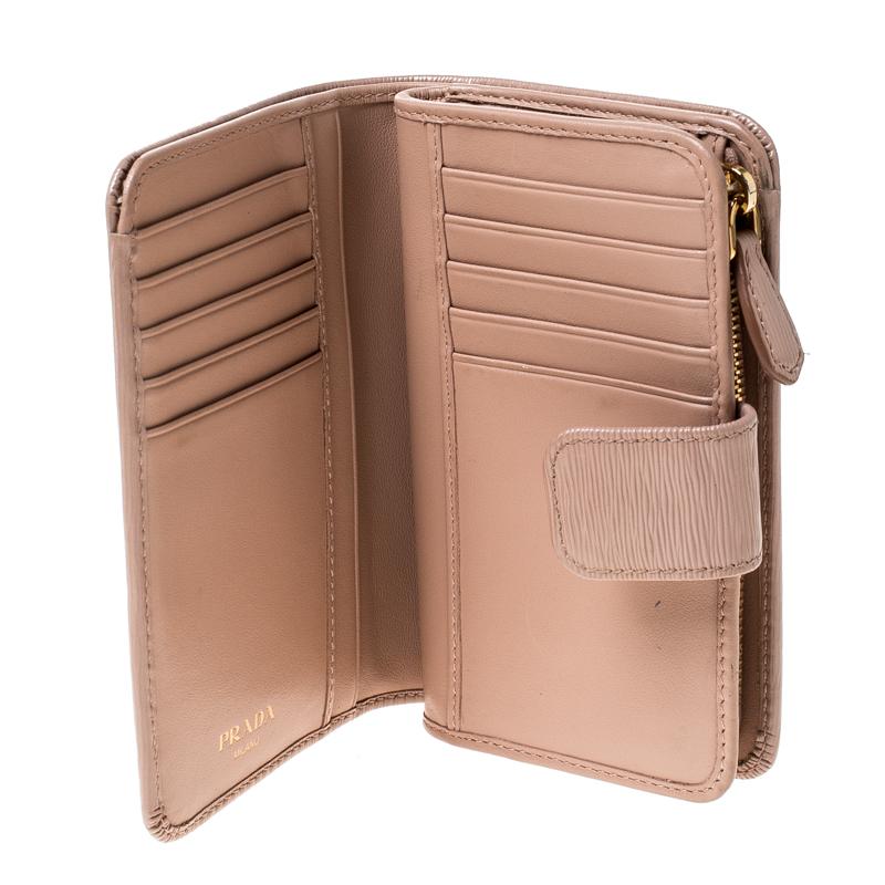 Stay organised in style with this wallet from Prada. It is crafted from leather and it features a zip compartment and a snap button that leads to multiple slots and open compartments. The wallet is compact and durable.

Includes: Original Box,