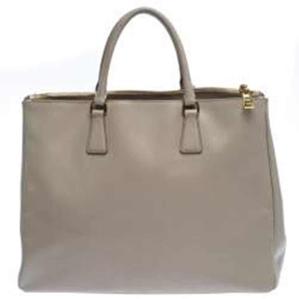 Feminine in shape and grand on design, this Double Zip tote by Prada will be a loved addition to your closet. It has been crafted from leather and styled minimally with gold-tone hardware. It comes with two top handles, two zip compartments and a