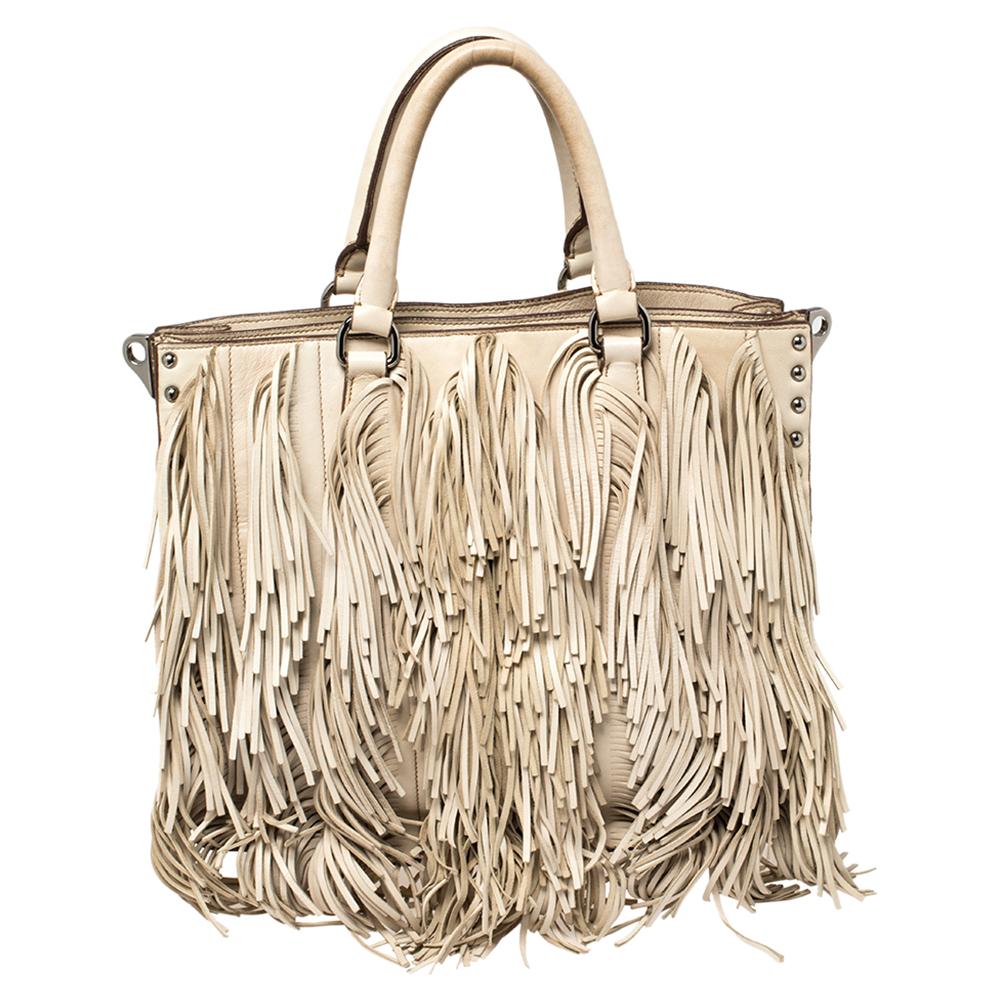 This Prada handbag is an example of the brand's fine designs that are skilfully crafted to project a classic charm. The tote is made of leather and enhanced with fringes, two top handles, a shoulder strap, and a spacious nylon interior.

Includes:
