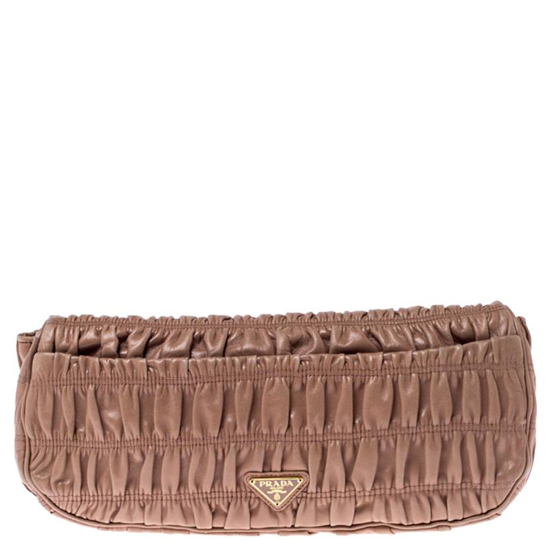 This Prade clutch is stylish and extremely versatile. It is crafted from Nappa Gaufre leather and comes in a lovely shade of beige. It features a ruched pattern throughout. It features a twist-lock on the front flap, a leather-lined interior that