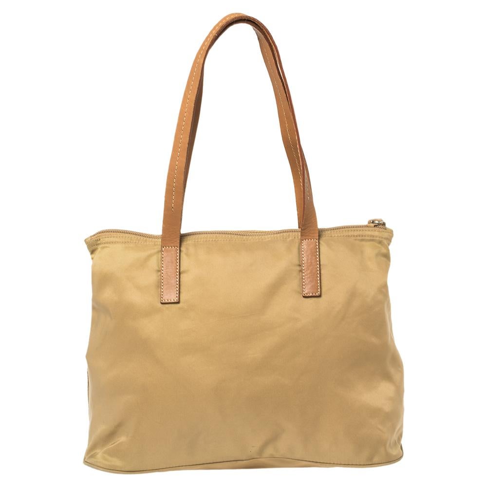 A smart choice for everyday use, this beige bag is versatile and durable. Designed by Prada, the nylon and leather tote has the triangular logo at the front, two top handles, and a nylon-lined interior.

