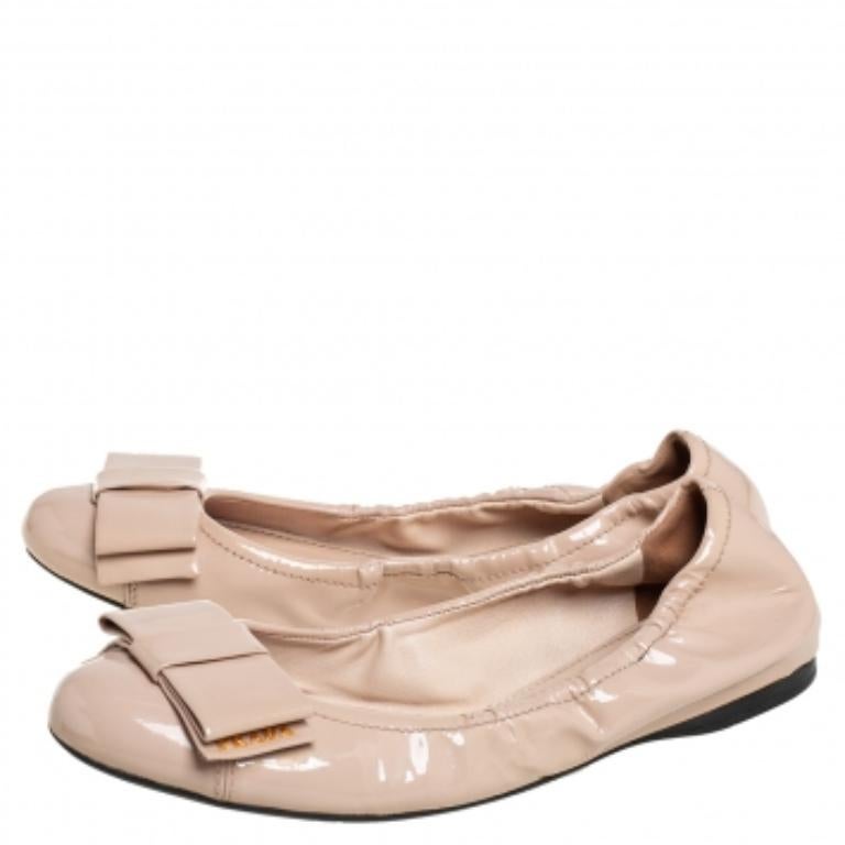 Estas bailarinas clásicas de Prada son el epítome de la sofisticación. Están exquisitamente confeccionados en charol brillante y forrados en piel. Están adornadas con lazos en las lengüetas. De estilo femenino, mantienen tus pies bonitos y cómodos.