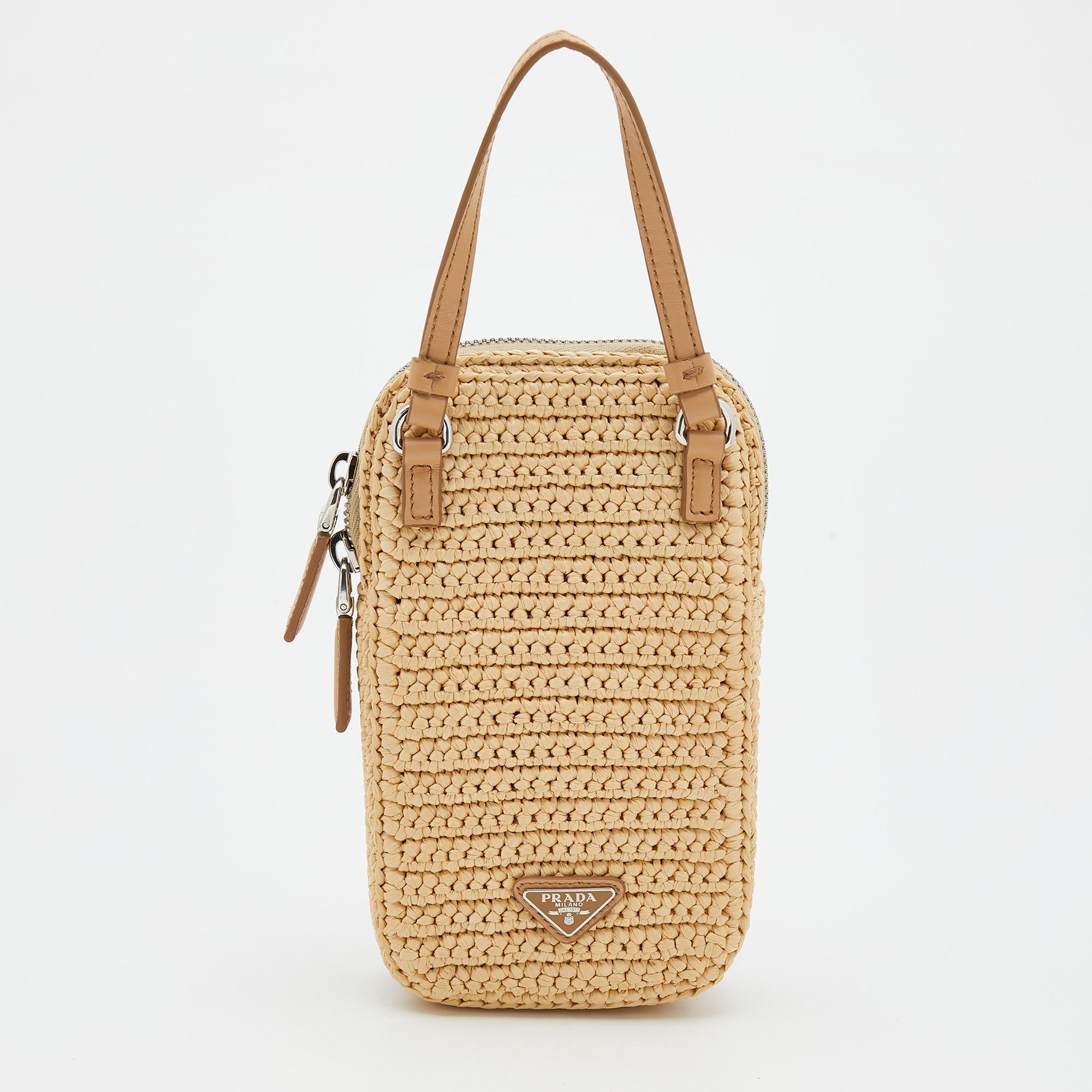 Complete your outfit of the day with this Prada crossbody bag! It is crafted from raffia and leather, with the brand logo decorating the front. It accommodates a nylon-lined interior and has a long strap. It easily holds cards, lipstick, and