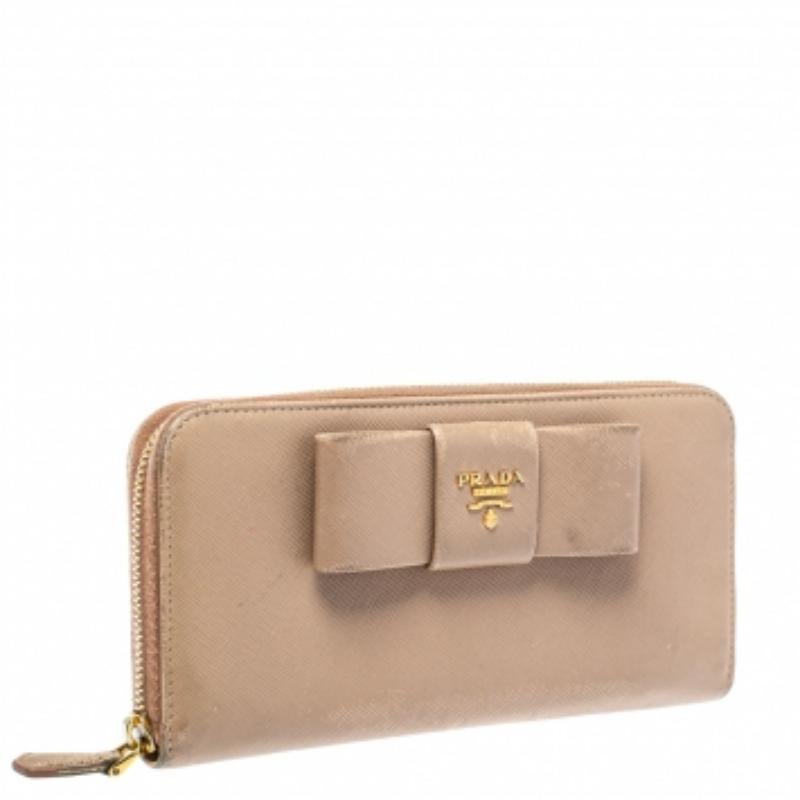 Store your monetary essentials in this stunning wallet from Prada. Durable and long-lasting, this wallet is crafted from fine quality Saffiano leather in a beige shade. The zip-around fastening secures multiple compartments, and the exterior is