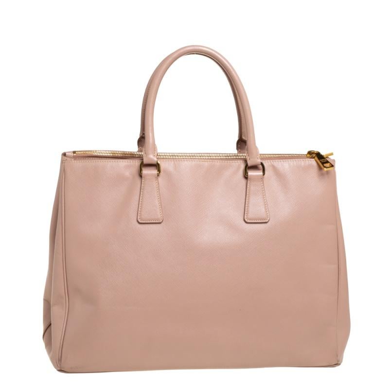 Feminin in Form und Design, wird diese Double Zip Galleria Tasche von Prada eine beliebte Ergänzung für Ihren Kleiderschrank sein. Sie wurde aus Saffiano-Leder gefertigt und minimalistisch mit goldfarbenen Beschlägen gestaltet. Sie verfügt über zwei