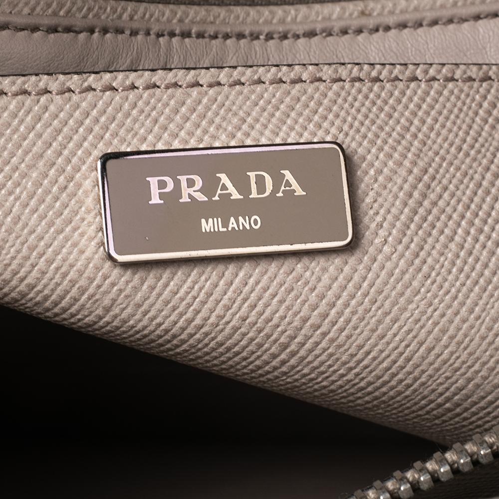 Add timeless style and luxury to your look with this stunning Prada Twin tote. Crafted in beige Saffiano leather, this bag can store all that you need in its spacious interior. The tote is detailed with the brand logo on the front, held by dual