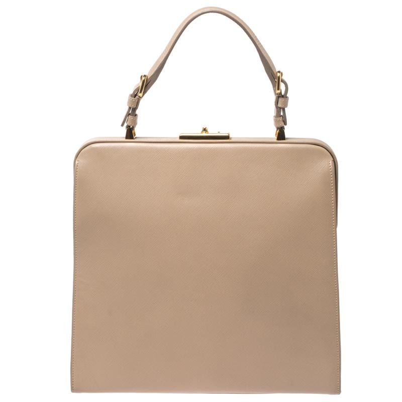 For all the Prada fans out there, your search for that perfect handbag ends here. This beige satchel is crafted from Saffiano Lux leather and comes with a single handle. The leather lined interior is spacious and will hold all your