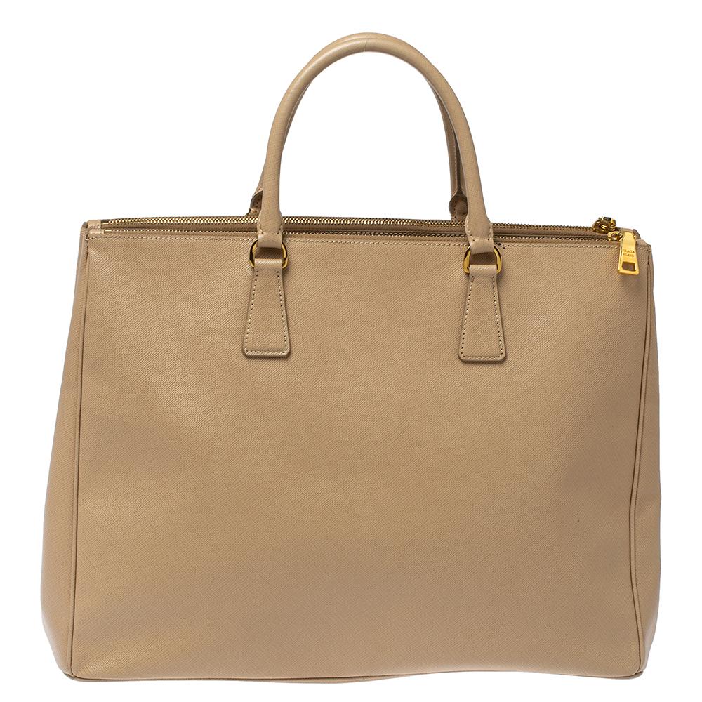 Feminine in shape and grand on design, this Double Zip tote by Prada will be a loved addition to your closet. It has been crafted from leather and styled minimally with gold-tone hardware. It comes with dual top handles, two zip compartments, and a