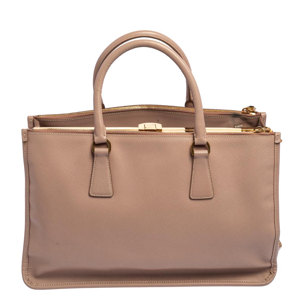 Feminin in der Form und großartig im Design, diese Double Zip-Tasche von Prada wird eine beliebte Ergänzung für Ihren Kleiderschrank sein. Sie wurde aus Saffiano-Leder gefertigt und mit goldfarbenen Beschlägen minimalistisch gestaltet. Sie hat zwei