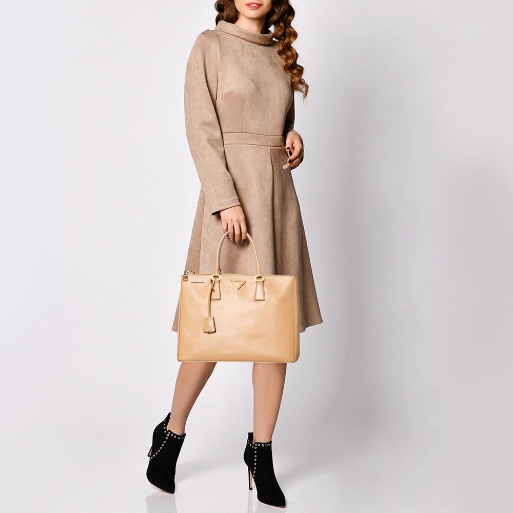 Loved for its classic appeal and functional design, Galleria is one of the most iconic and popular bags from the house of Prada. This beauty in beige is crafted from Saffiano Lux leather and is equipped with two top handles, the brand logo at the