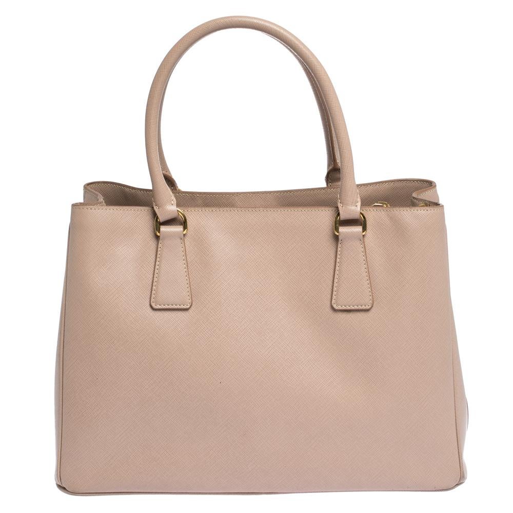 This Galleria tote by Prada will be a loved addition to your closet. It has been crafted from Saffiano Lux leather and styled minimally with gold-tone hardware. It comes with two top handles and a perfectly-sized main compartment. The bag is