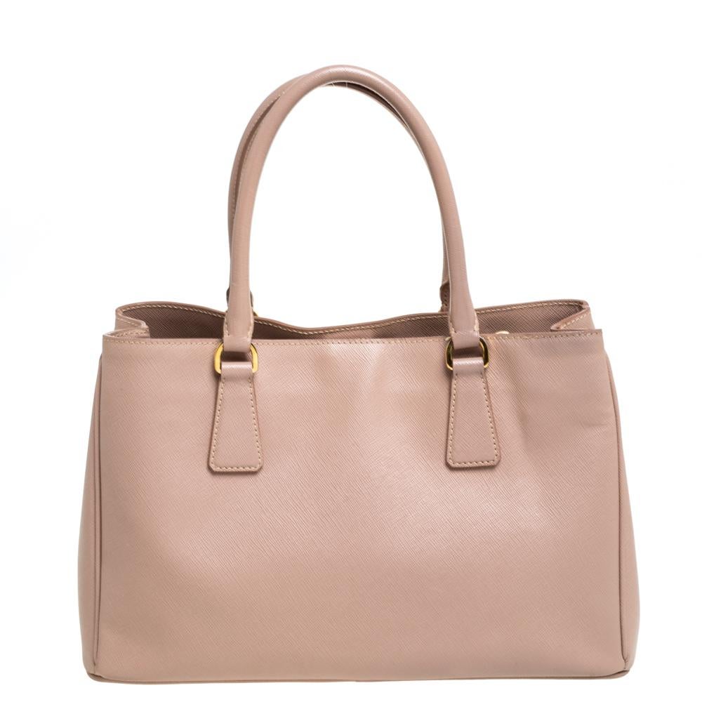 Feminine in shape and grand on design, this Zip tote by Prada will be a loved addition to your closet. It has been crafted from leather and styled minimally with gold-tone hardware. It comes with two top handles and a nylon-lined interior housing a