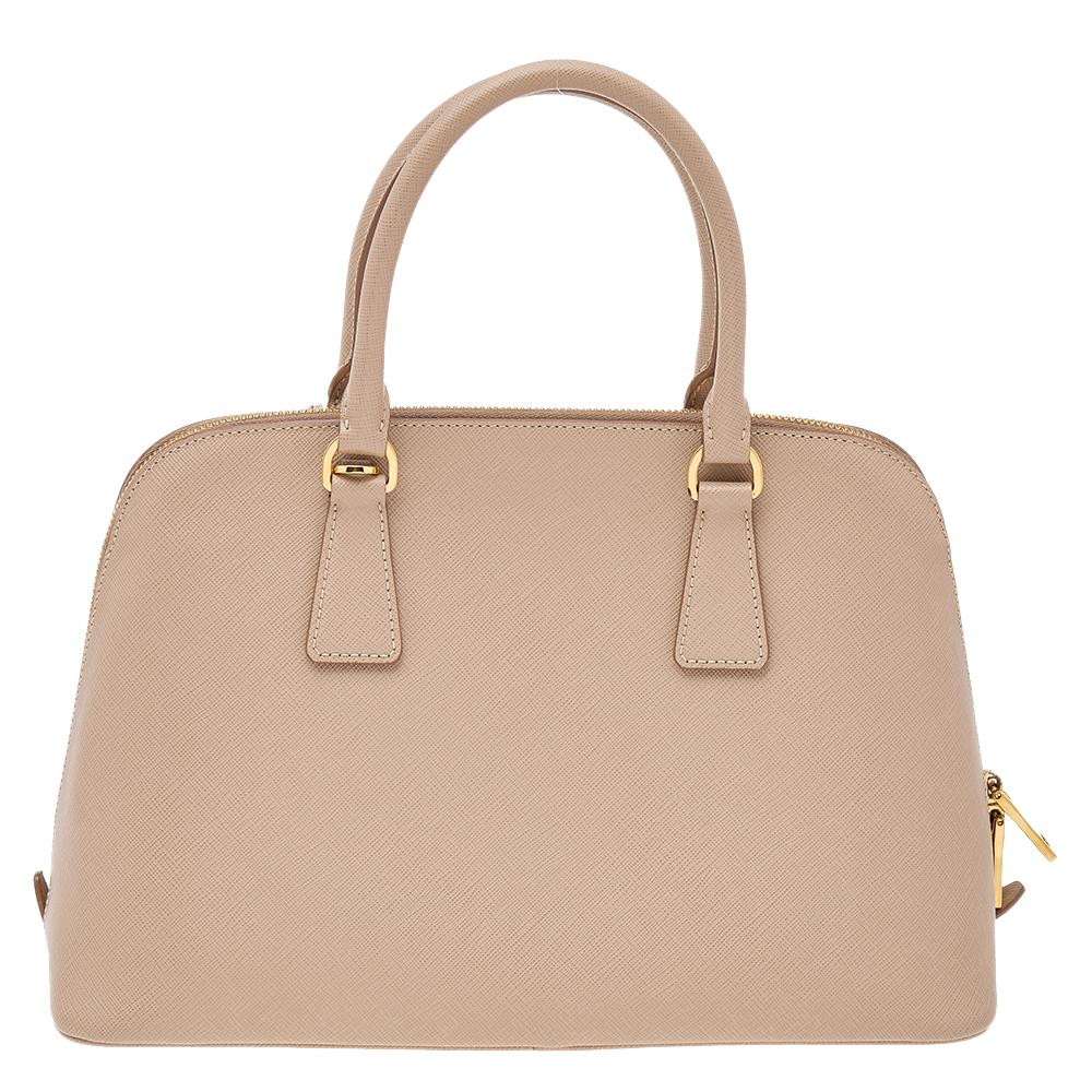 This stunning Promenade tote is high on appeal and style. Dazzling in a classy beige shade, the bag is crafted from Saffiano Lux leather and features two rolled handles. The zip closure leads way to a nylon interior with enough space for your