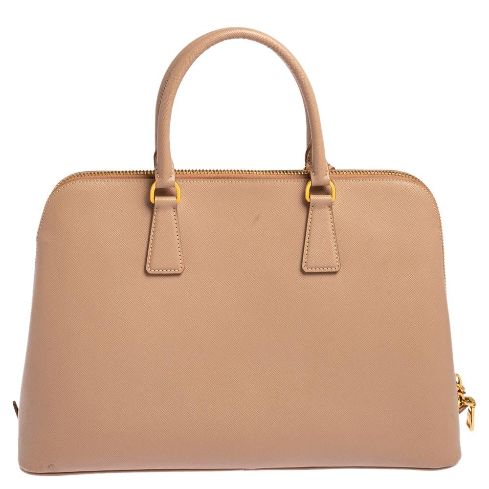 This stunning Promenade bag is high in appeal and style. Dazzling in a classy beige shade, the bag is crafted from Saffiano Lux leather and features two rolled handles. The zip closure leads way to a nylon-lined interior with enough space for your