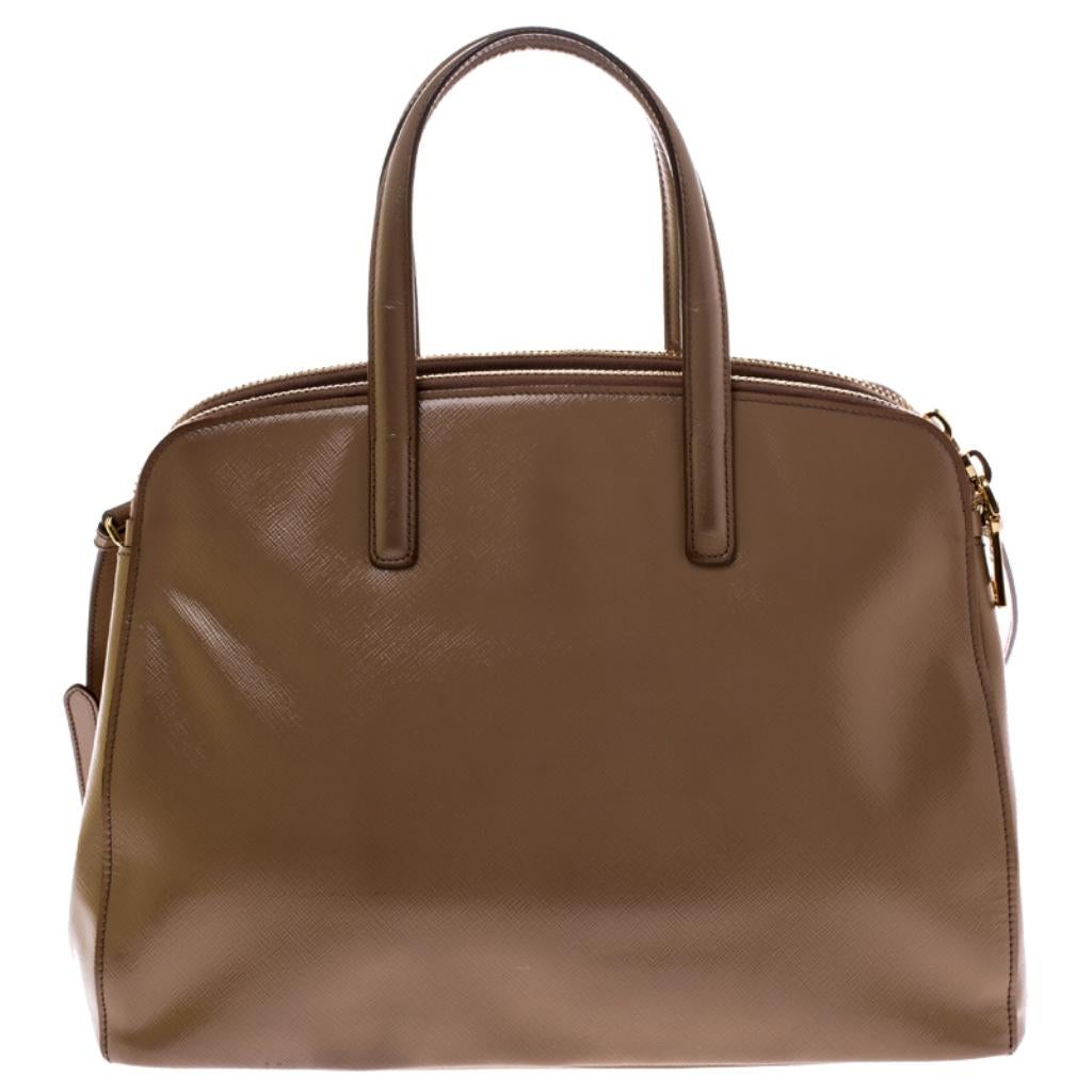 Grand in design, this Double Zip Spazzolato tote by Prada will be a loved addition to your closet. It has been crafted from Saffiano patent leather and styled minimally with gold-tone hardware. It comes with two top handles, two zip compartments and