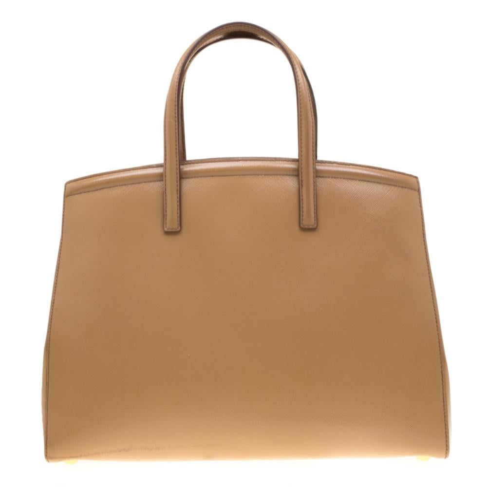 This stunning tote is high on appeal and style. Dazzling in a gorgeous beige shade, the bag is crafted from Saffiano patent leather and features two top handles. The snap button leads way to a fabric-lined interior with enough space for your