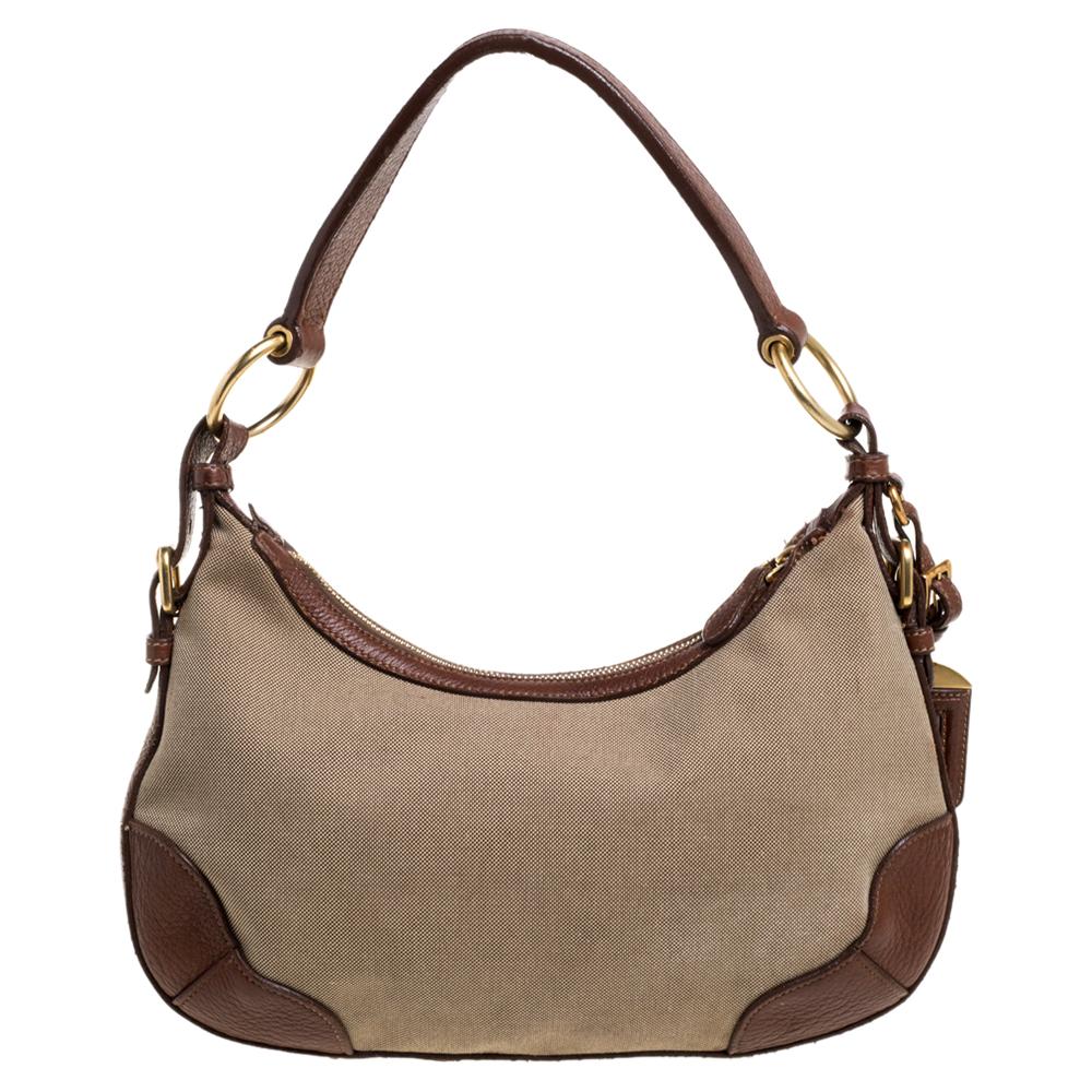 Diese beige/braune Tasche von Prada ist aus Jacquard-Canvas und Leder gefertigt. Die Tasche hat einen einzelnen Henkel, ein Logo auf der Vorderseite und einen Reißverschluss, der zu einem Innenraum aus Nylon führt. Diese Hobo ist ideal für den