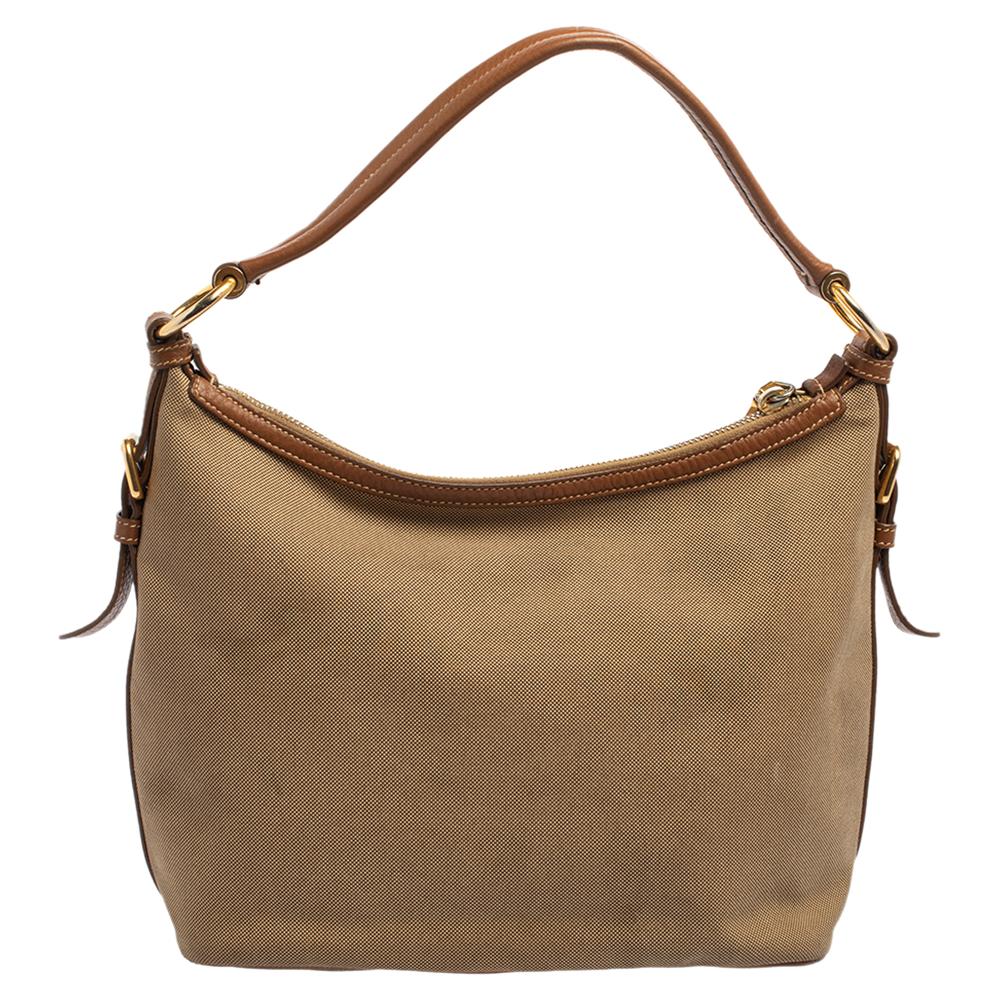 This beige & tan bag from Prada is crafted from jacquard canvas and leather. The bag comes with a single handle, logo detailing on the front, and a zipper that opens to a nylon interior. This hobo is ideal for everyday use.

