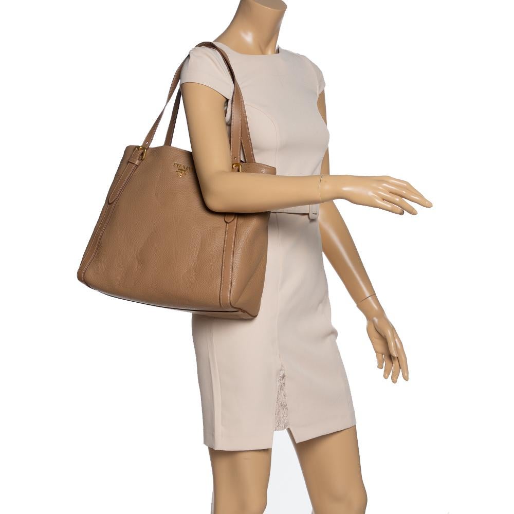 Prada brings you this handy tote that will dutifully hold all your necessities. It has been crafted from subtle beige-colored leather and features dual handles. The nylon-lined interior is spacious and houses a zip pocket. This Shopper tote is your