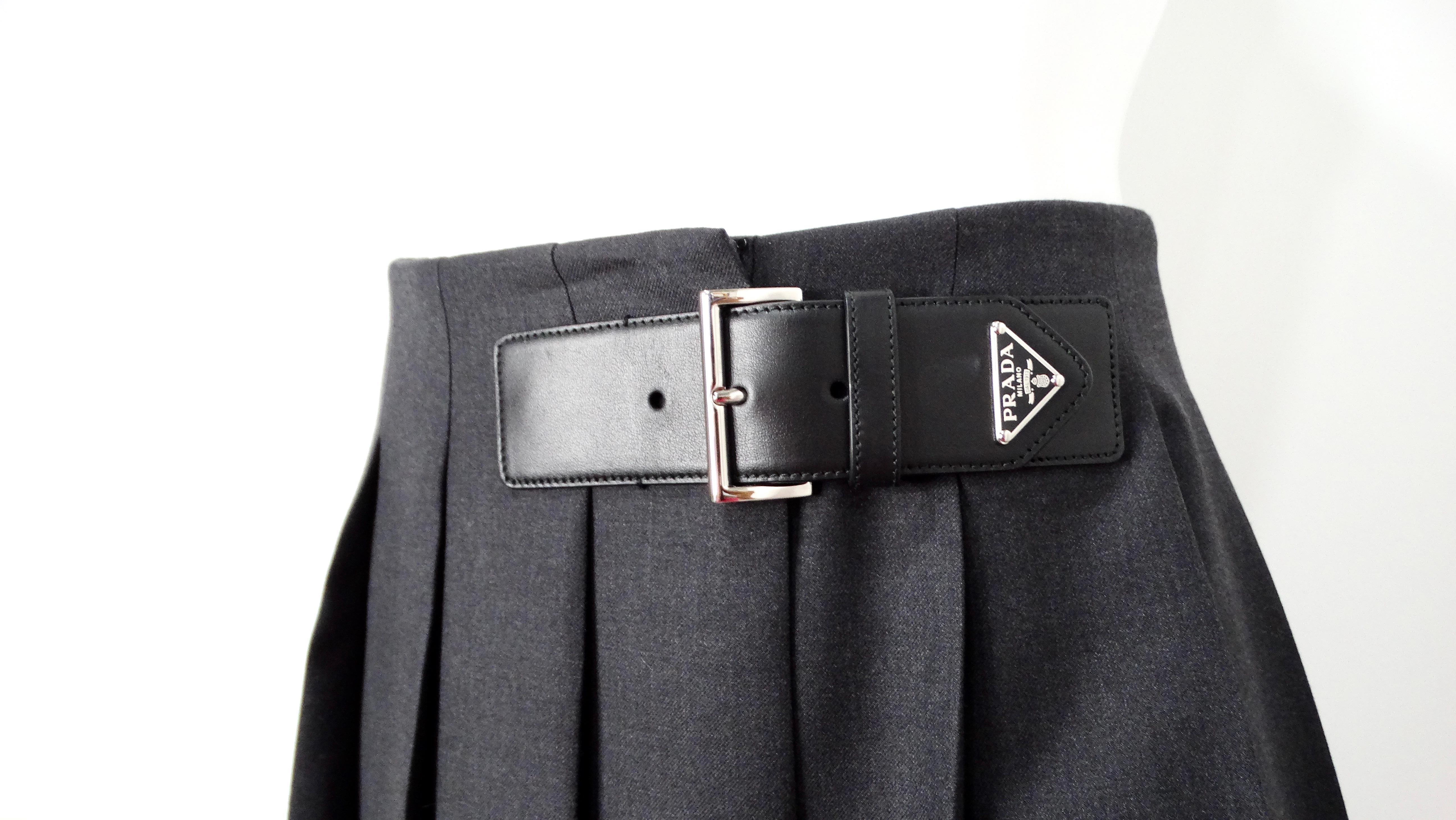 La gonna midi a pieghe in gabardina grigia di Prada emana un'eleganza senza tempo con un tocco contemporaneo. Realizzata in tessuto gabardine di alta qualità, la gonna è caratterizzata da una sofisticata tonalità di grigio che si abbina facilmente a