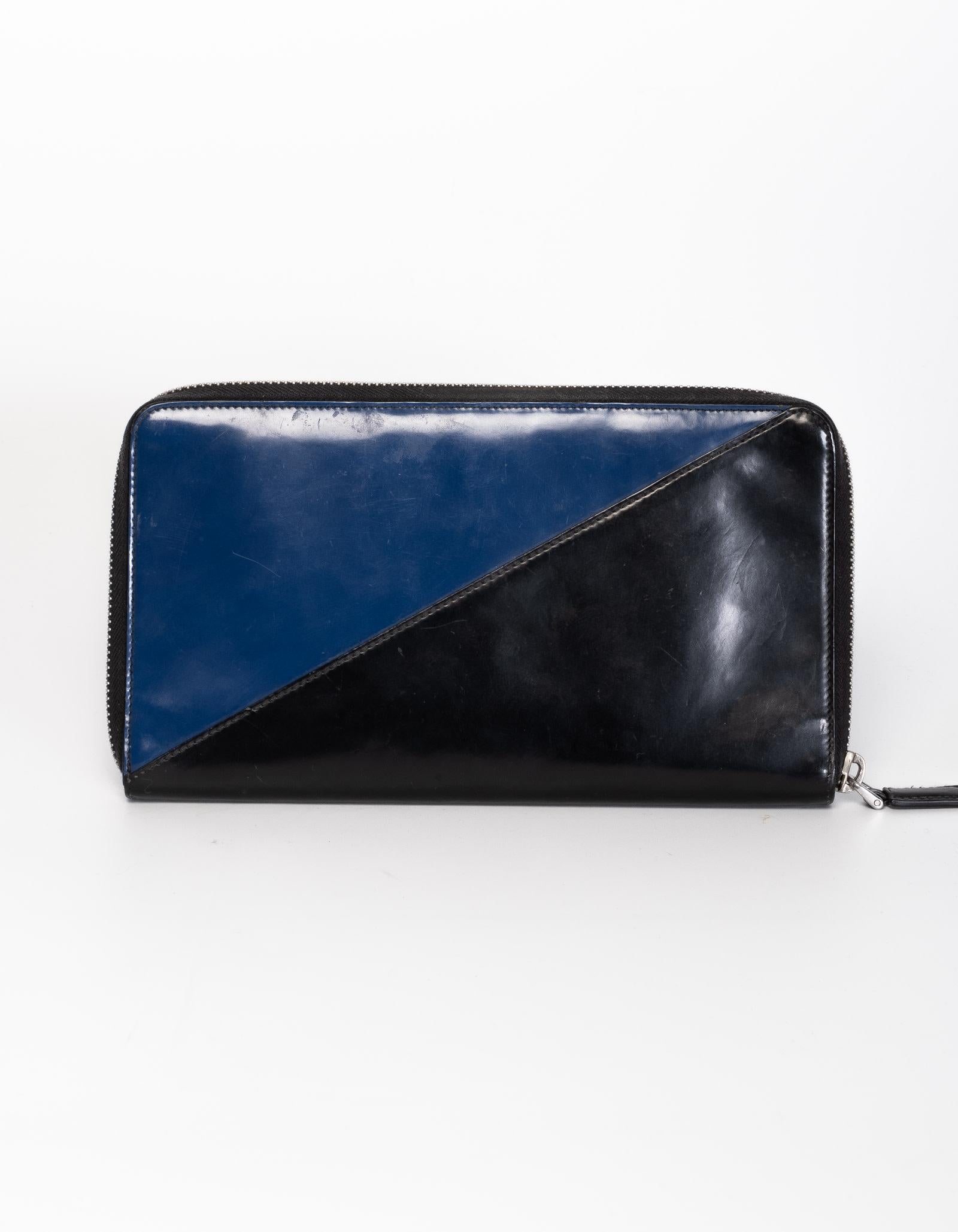 This Prada wallet features black and blue leather with zip around closure and interior with mini card slots.

COLOR: Black and blue
MATERIAL: Leather 
MEASURES: H 9” x L 4.5” x D .5”
COMES WITH: Dust bag
CONDITION: Good - wallet shows signs of wear