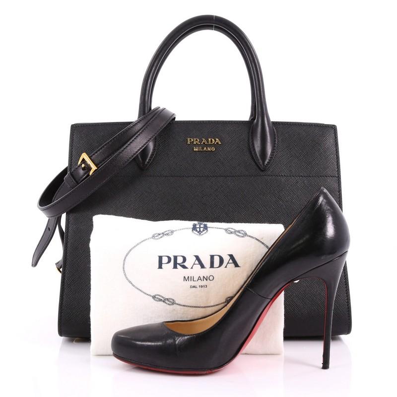 This Prada Bibliotheque Handbag Saffiano Leather with City Calfskin Medium, crafted from black saffiano leather with calfskin leather, features dual rolled leather handles, expandable concertina sides, and gold-tone hardware. It opens to a black and