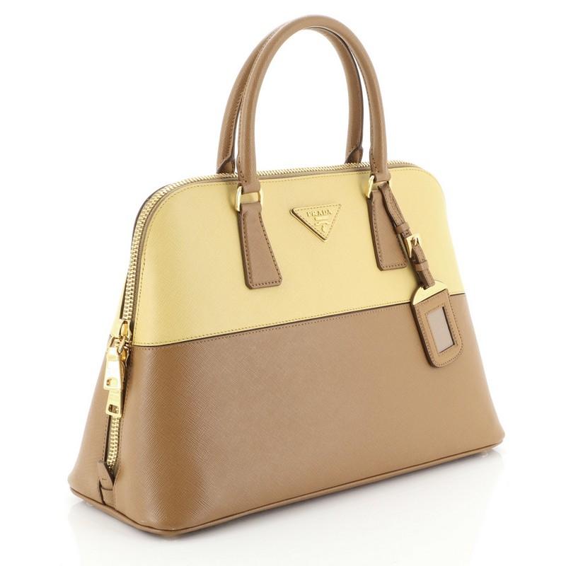 This Prada Bicolor Promenade Bag Saffiano Leather Medium, crafted from brown and neutral saffiano leather, features dual rolled handles, protective base studs and gold-tone hardware. Its two-way zip closure opens to a neutral fabric interior with