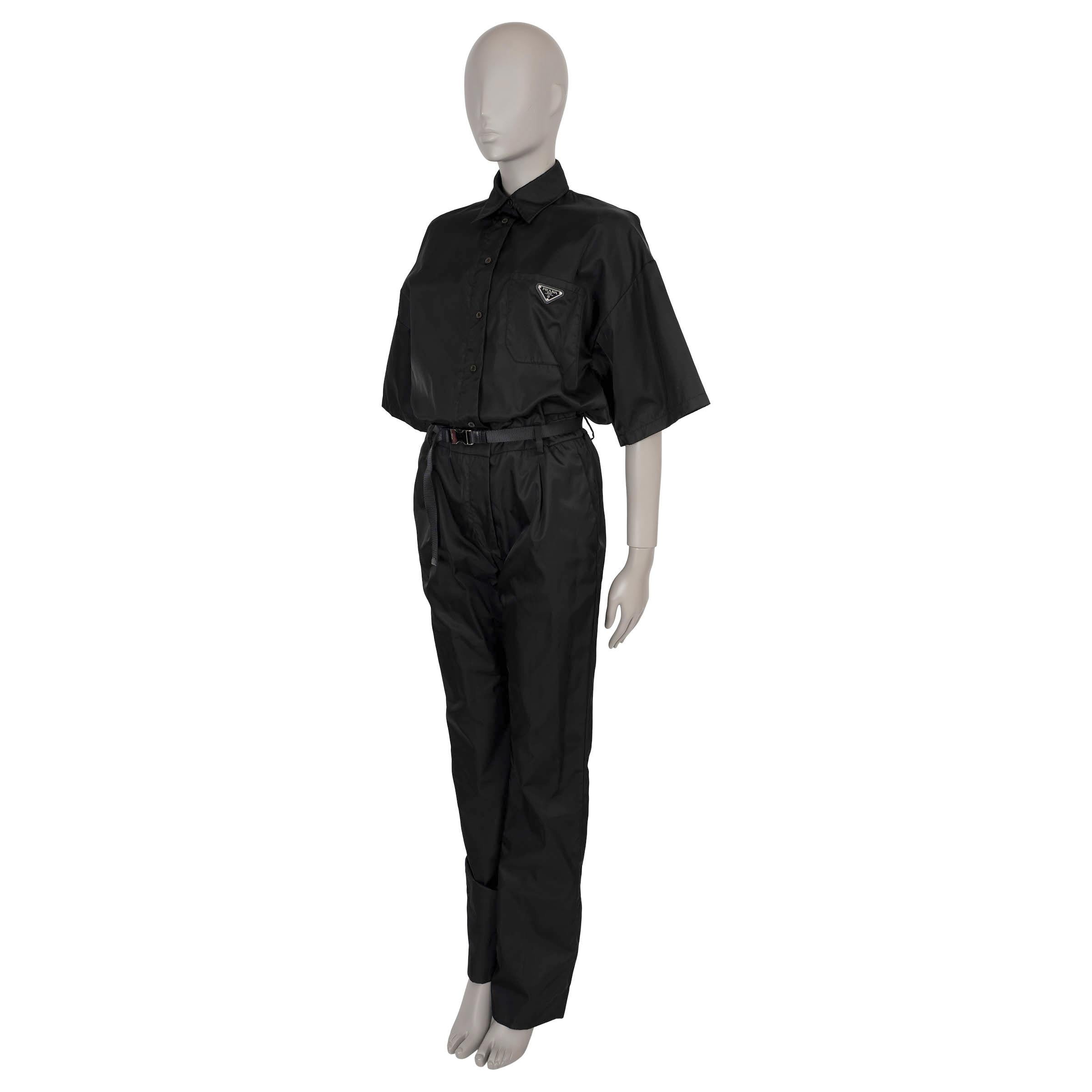 This 100% authentic Prada Re-Nylon jumpsuit in black polyamide combines contemporary style with sustainable materials. It features a classic collar, wide half-sleeves, and a chest patch pocket adorned with the iconic enamelled Triangle logo on a