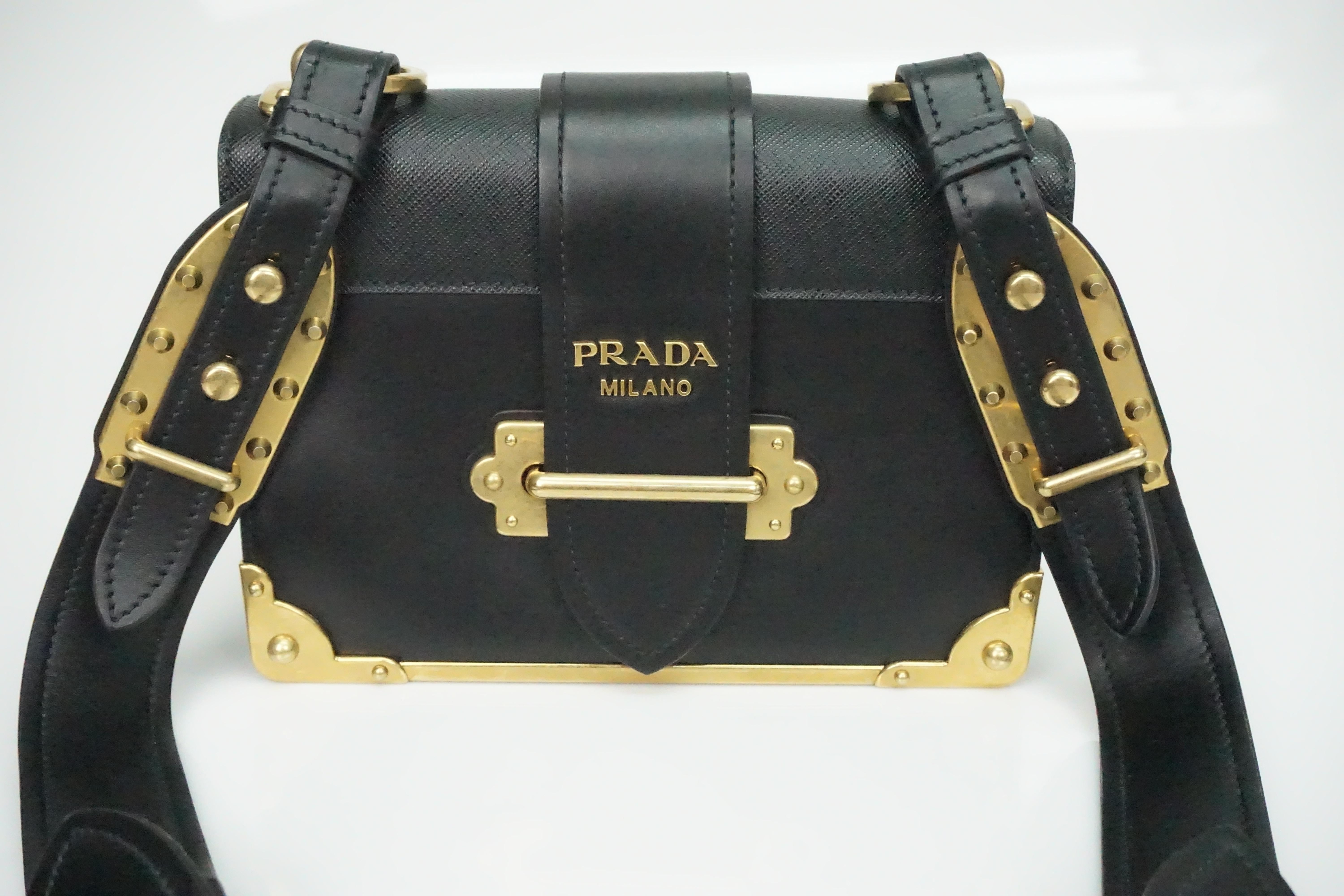 Prada Black Cahier Shoulder Bag W/ Gold Hardware   This fantastic bag is in excellent condition. There are gold metal plates on the bottom front and back of the bag. There are also golden plates on the beginning and the end of the straps with stud