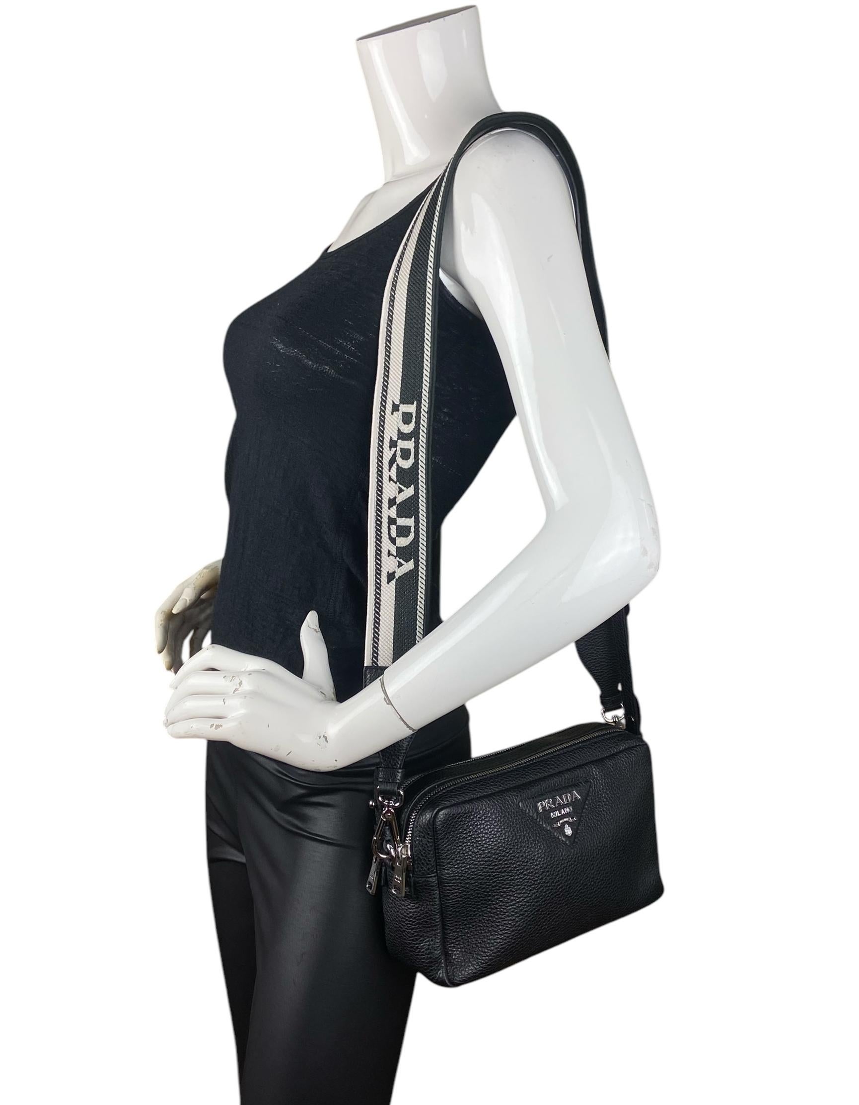 Prada Black Calfskin Leather Flou Camera Crossbody Bag. This versatile bag features a two straps, one leather and one woven

Color: Black
Hardware: Silvertone
Materials: Calfskin leather
Lining: Logo printed fine textile
Closure/Opening: Double zip